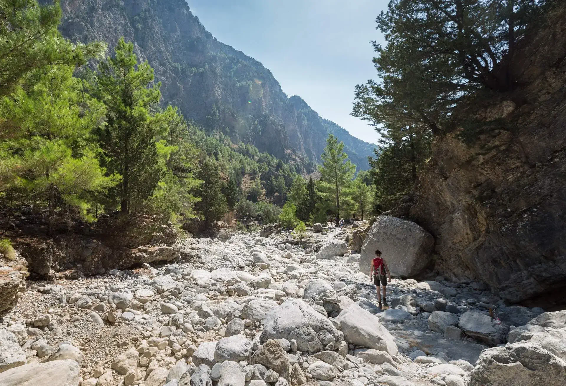 A woman on her way through the Samaria Gorge, Crete. The gorge is in southwest Crete in the regional unit of Chania and a major tourist attraction of the island . It was created by a small river running between the White Mountains and Mt. Volakias. The gorge is 16 km long, starting at an altitude of 1,250 m (4100 ft.)at the northern entrance, and ending at the shores of the Libyan Sea in Agia Roumeli.