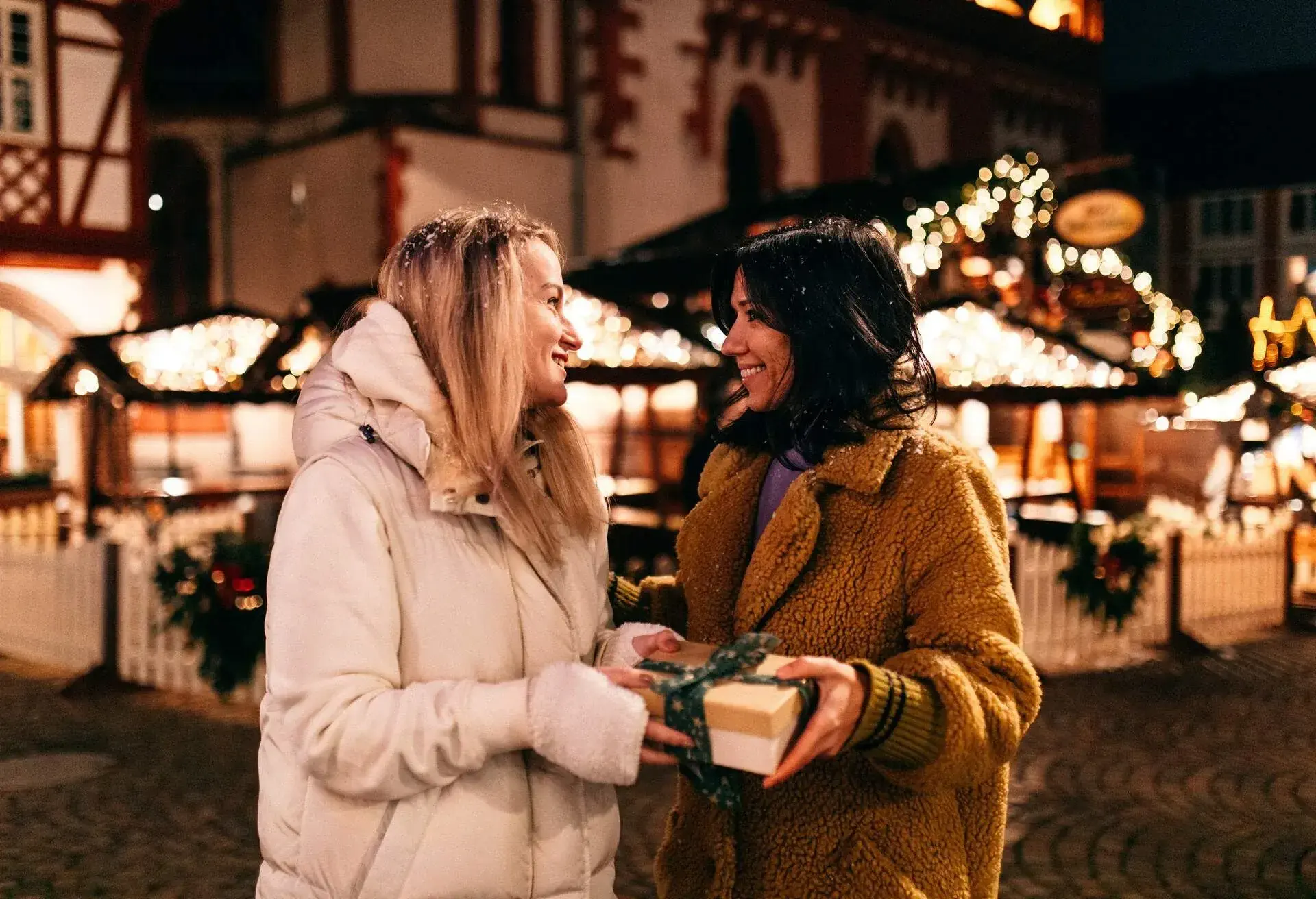 Woman giving her friend a wrapped Christmas gift.