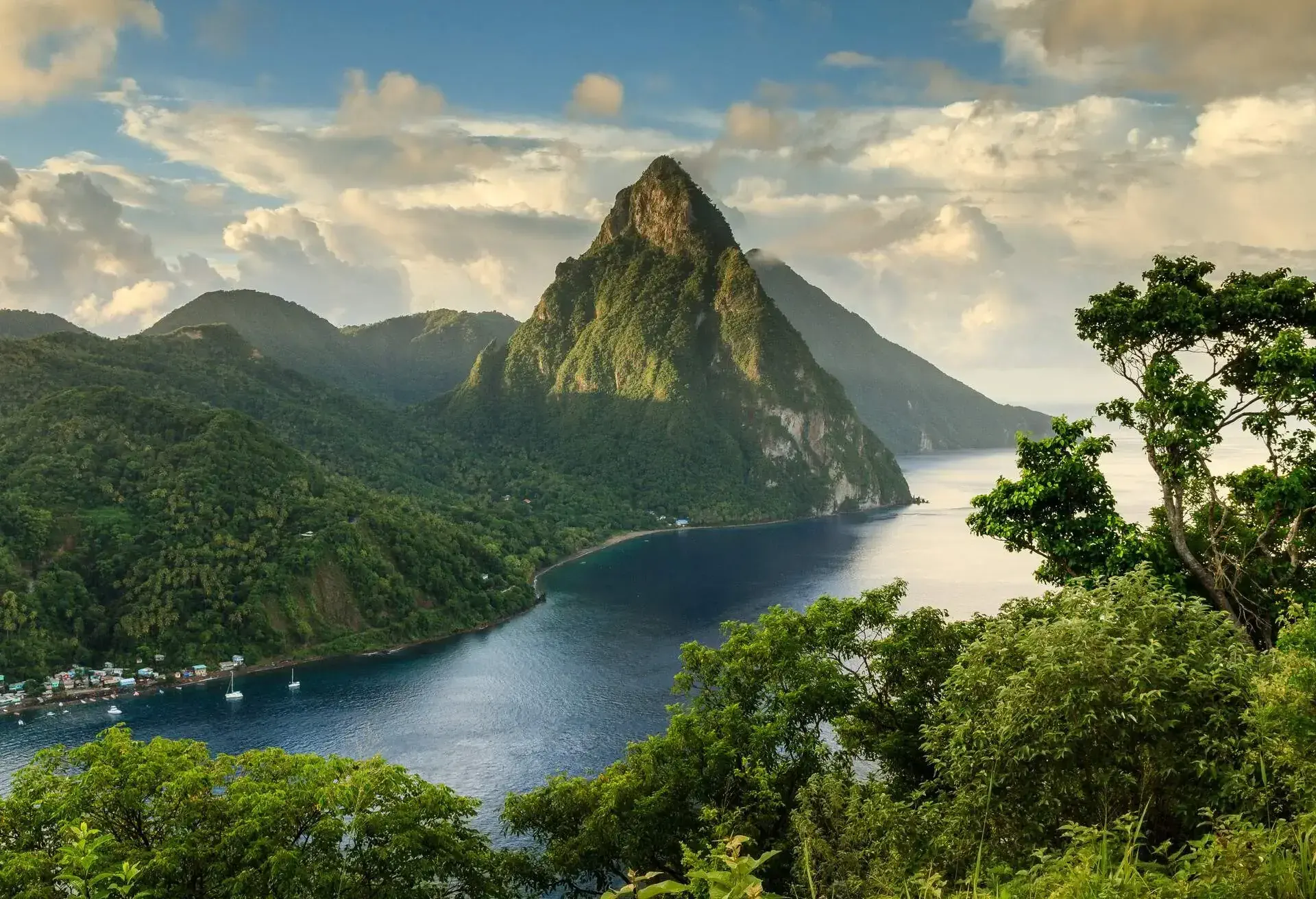 A picturesque paradise with a verdant and mountainous island surrounded by the tranquil sea under the cloudy blue sky.