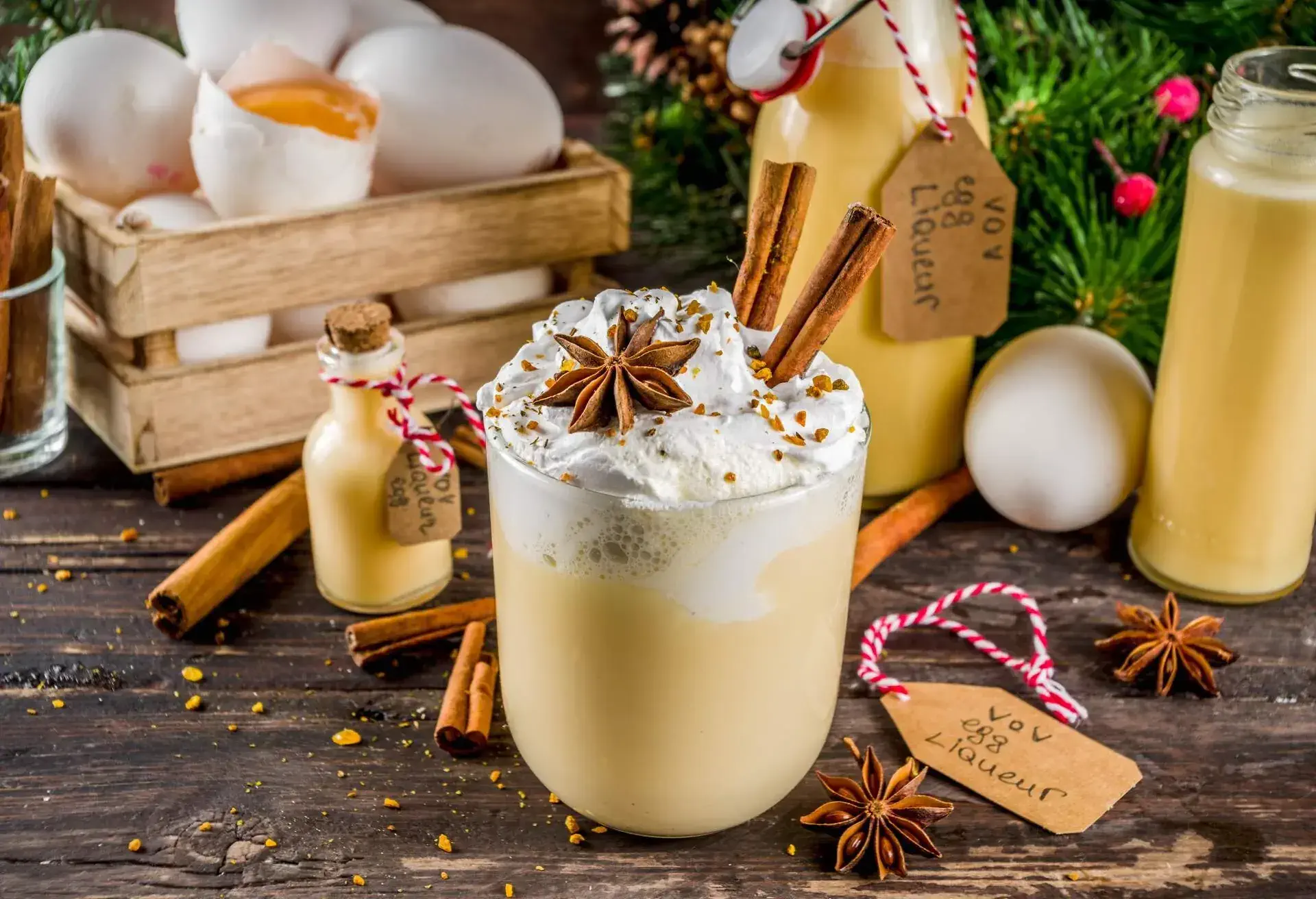 A cup of creamy egg liqueur topped with whipped cream, cinnamon sticks, and star anise.