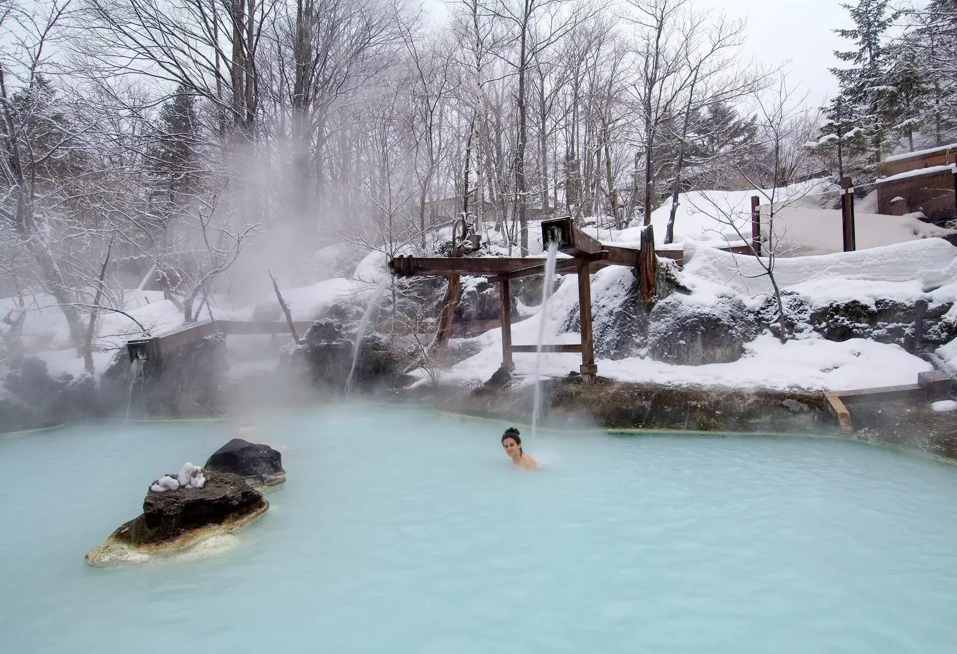 A caucasian woman have a bath in an open air hotspring. awanoyu onsen. shiraone-onsen azumi. matsumoto. nagano prefecture. chubu region. japan.