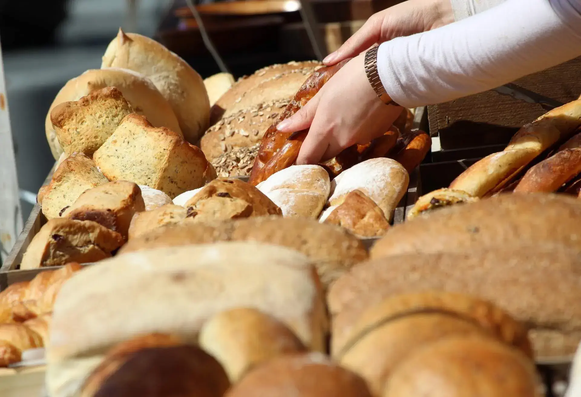 Woman hands placing pastries among bread and cakes on a market stall
