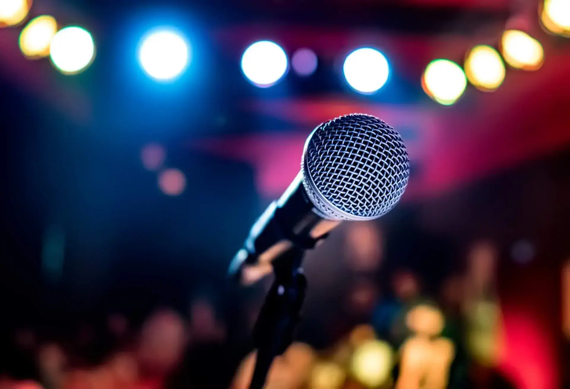 A microphone on a stand against a bokeh of multi-coloured lights.