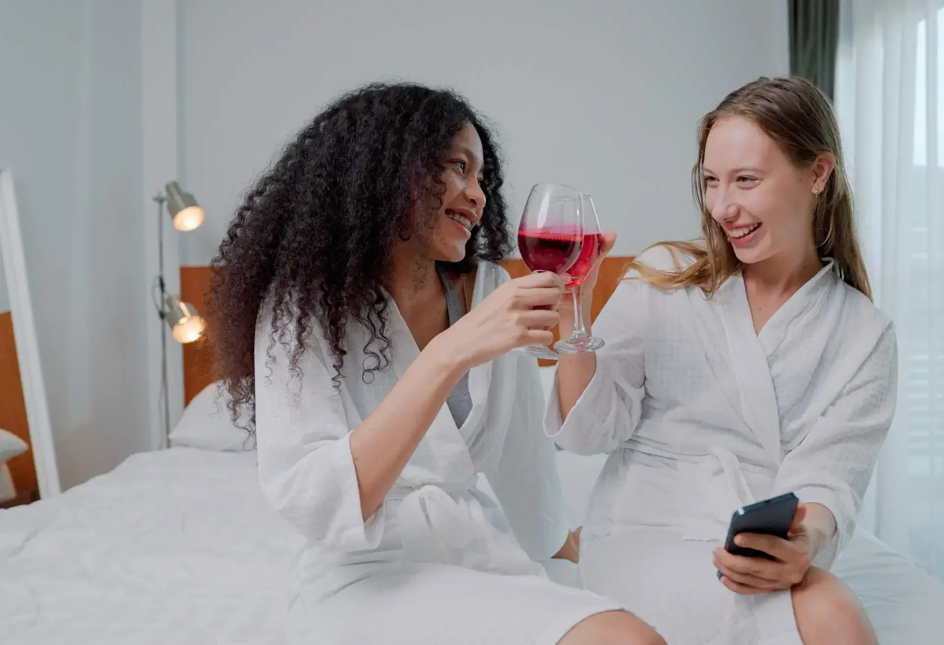 A young lesbian couple laughing at funny stories they tell each other while relaxing in a luxury hotel.