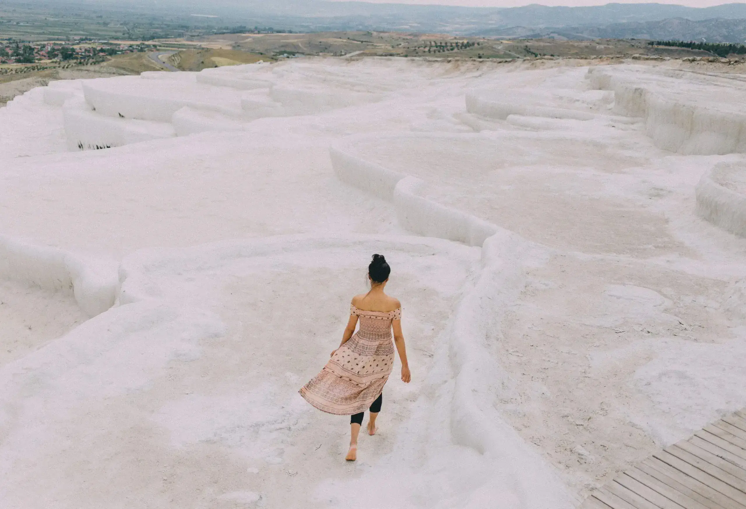 A lone individual walks along a mesmerising, snow-white limestone landscape, characterised by its terraced formations.