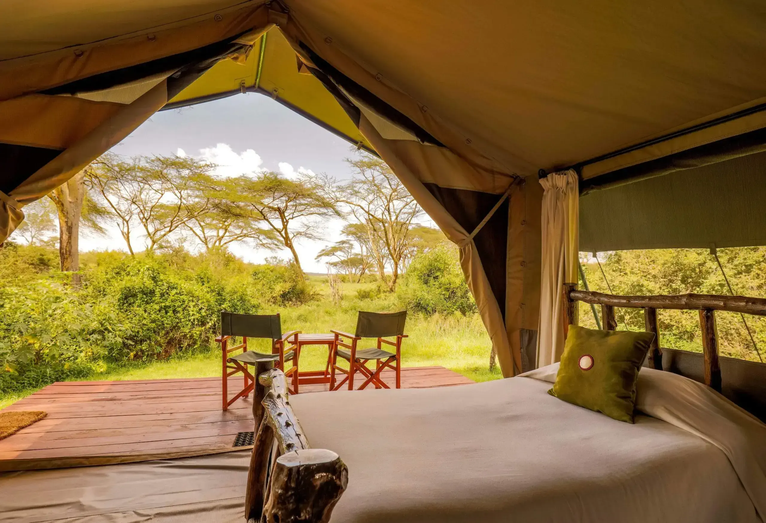 A yurt with a bed and a small terrace equipped with a table and two chairs.