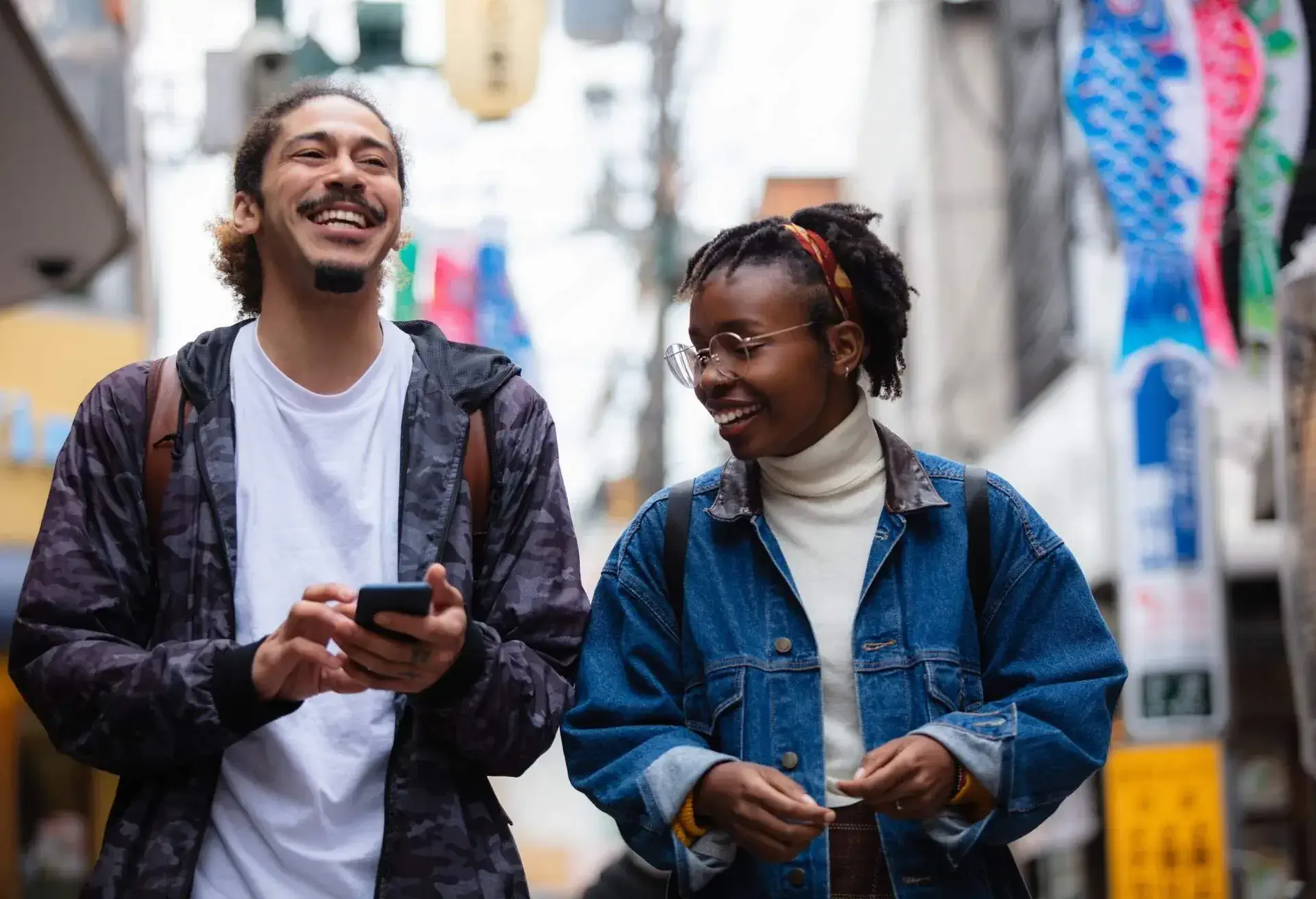 Two young people laugh as they walk along the sidewalk in Tokyo, Japan.