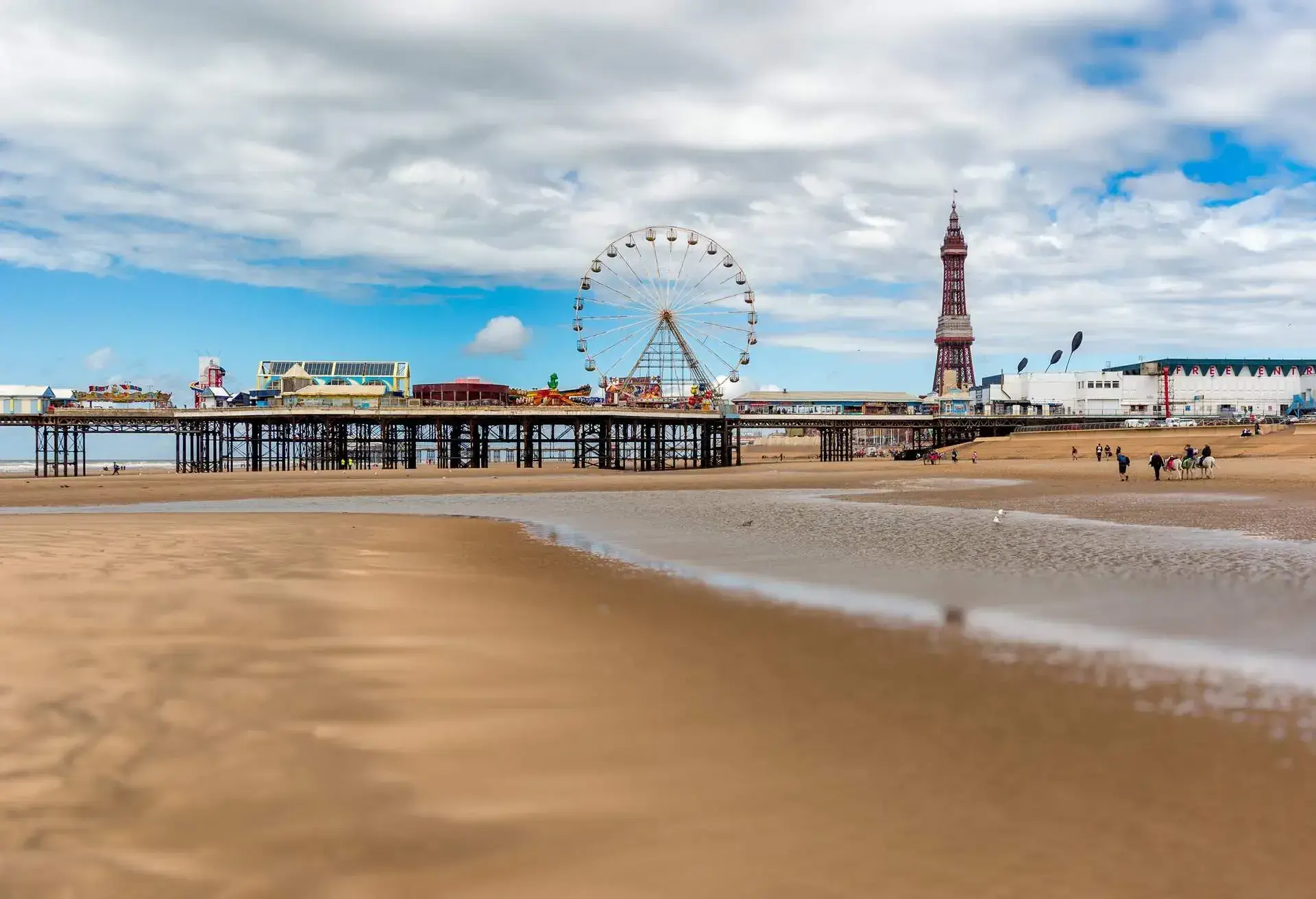 The landscape of Central Pier with an amusement park and Ferris wheel at low tide in summer.