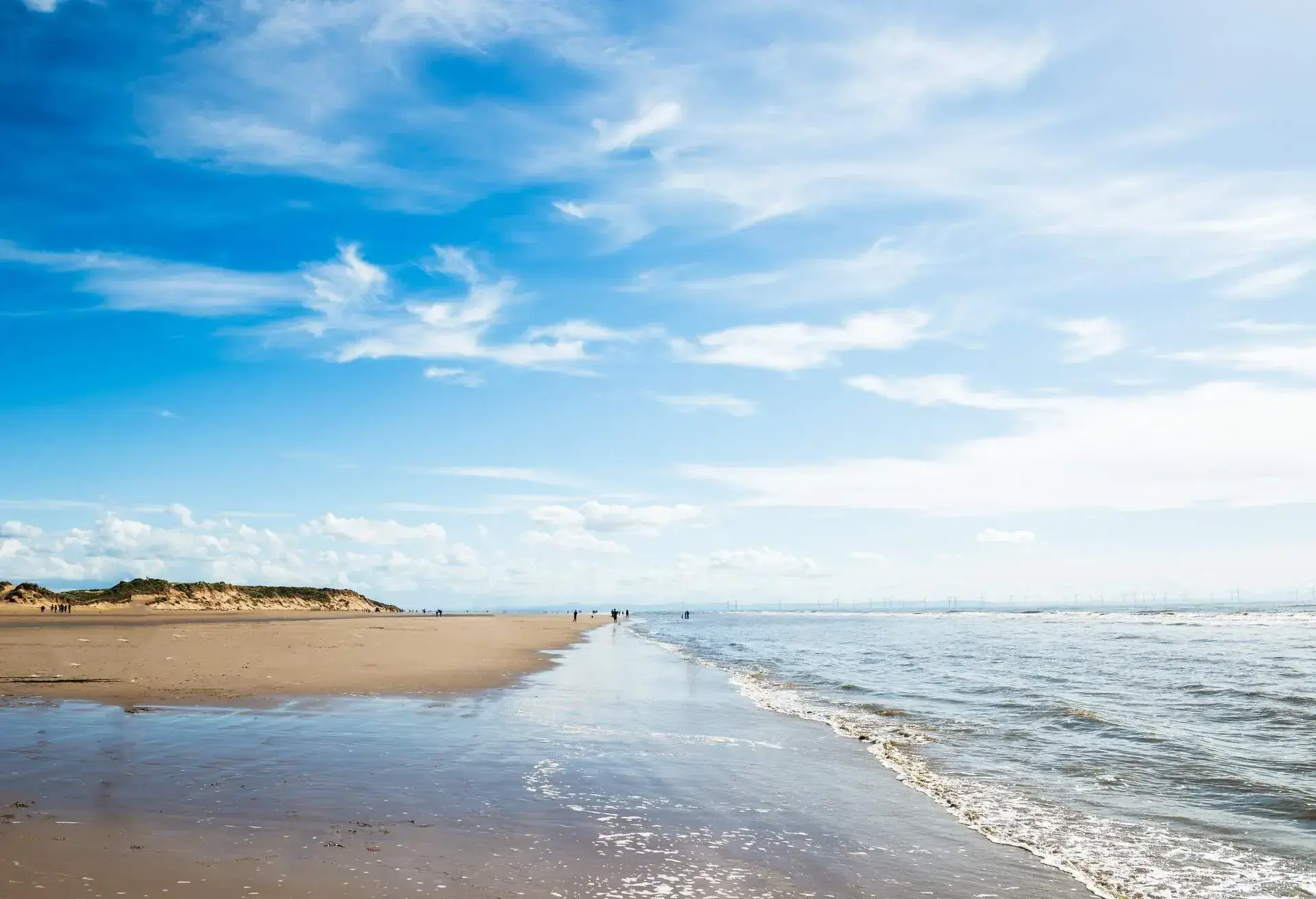 A sandy shore by the beach against the cloudy blue sky.
