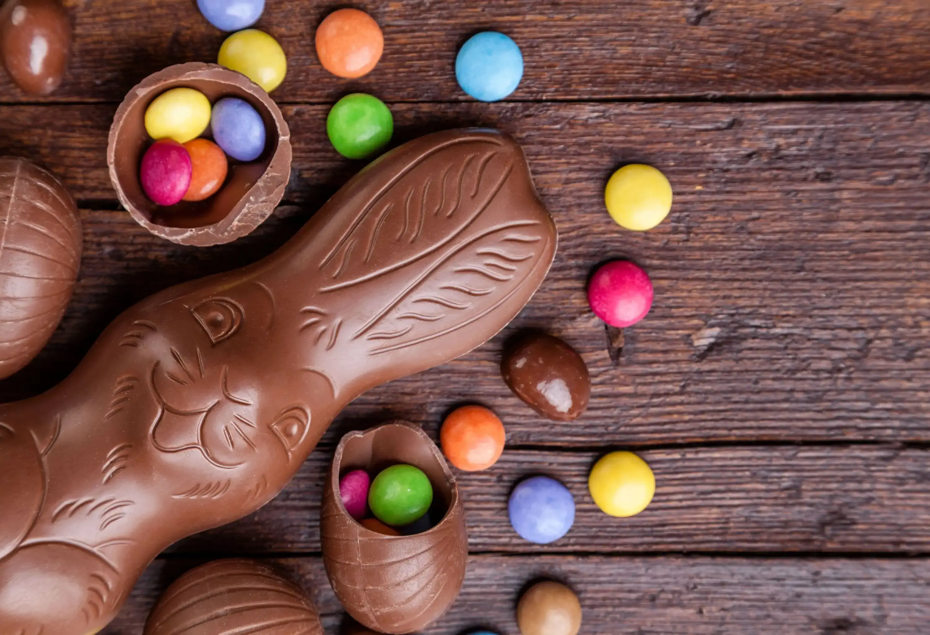 A chocolate shaped like a rabbit and cracked chocolate eggs with colourful circle candies.
