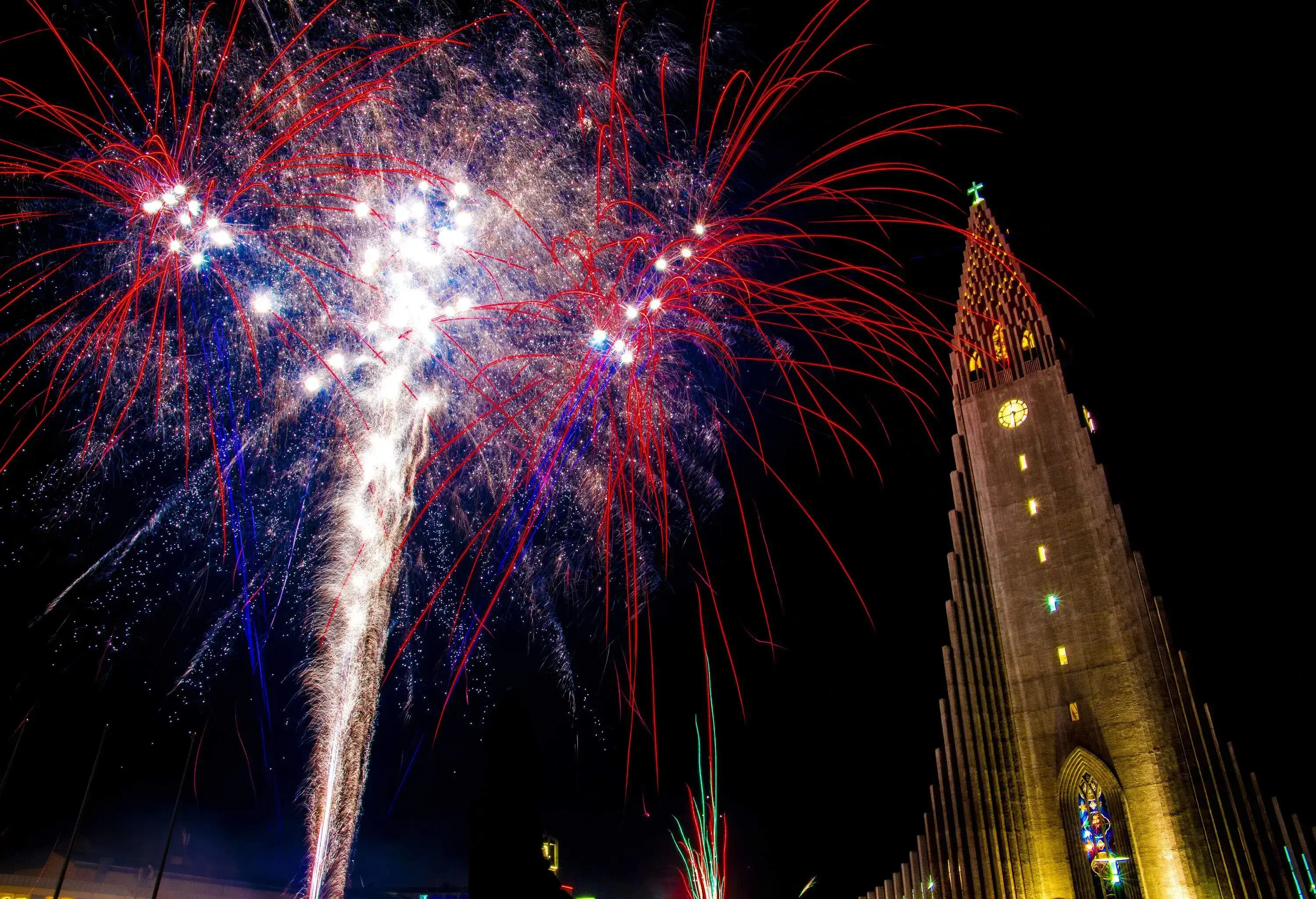 The spire of Hallgrmskirkja and the exploding fireworks against the night sky.