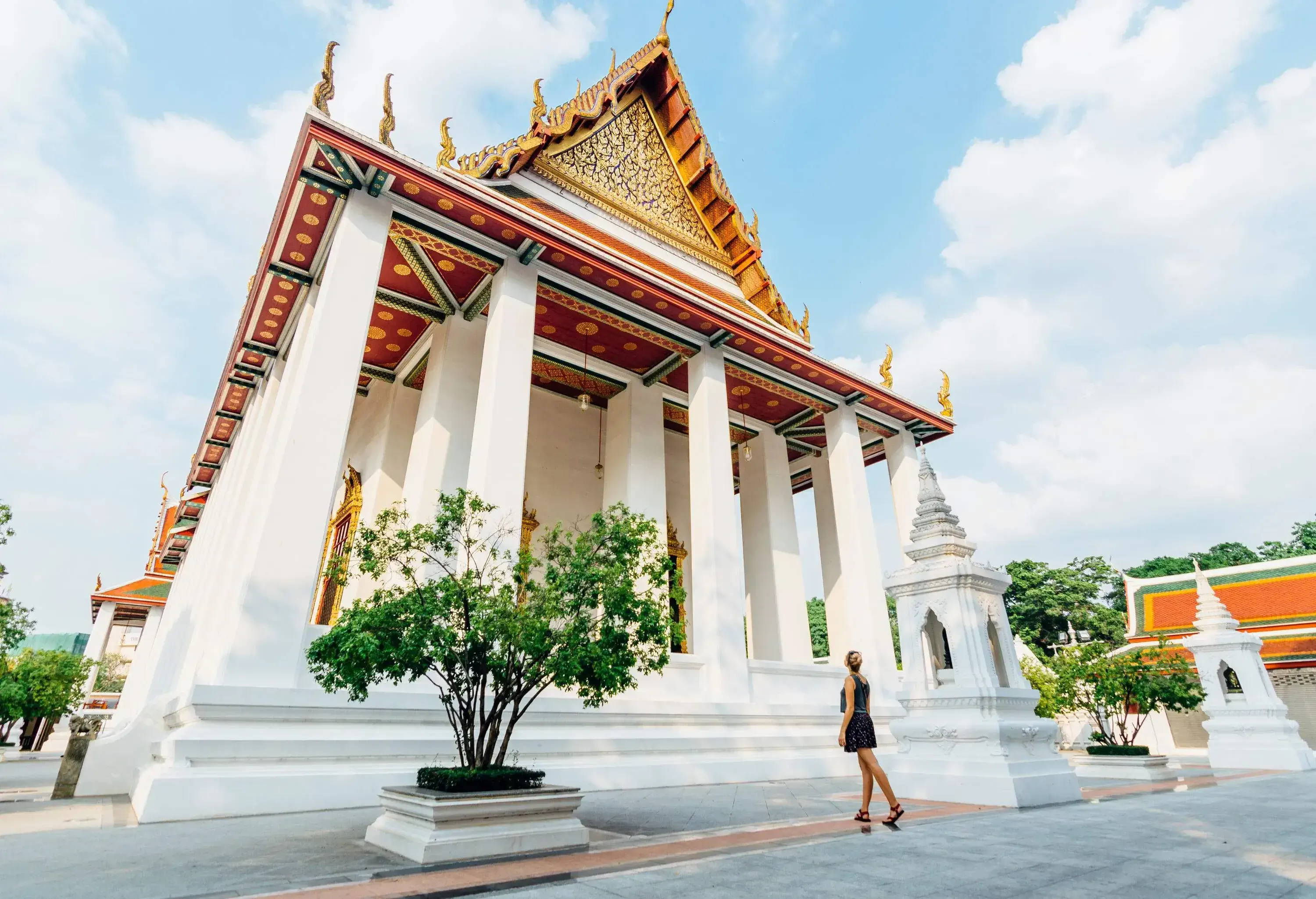 A woman gazing up at a temple with a fascinating ceiling design and an ornate pediment.