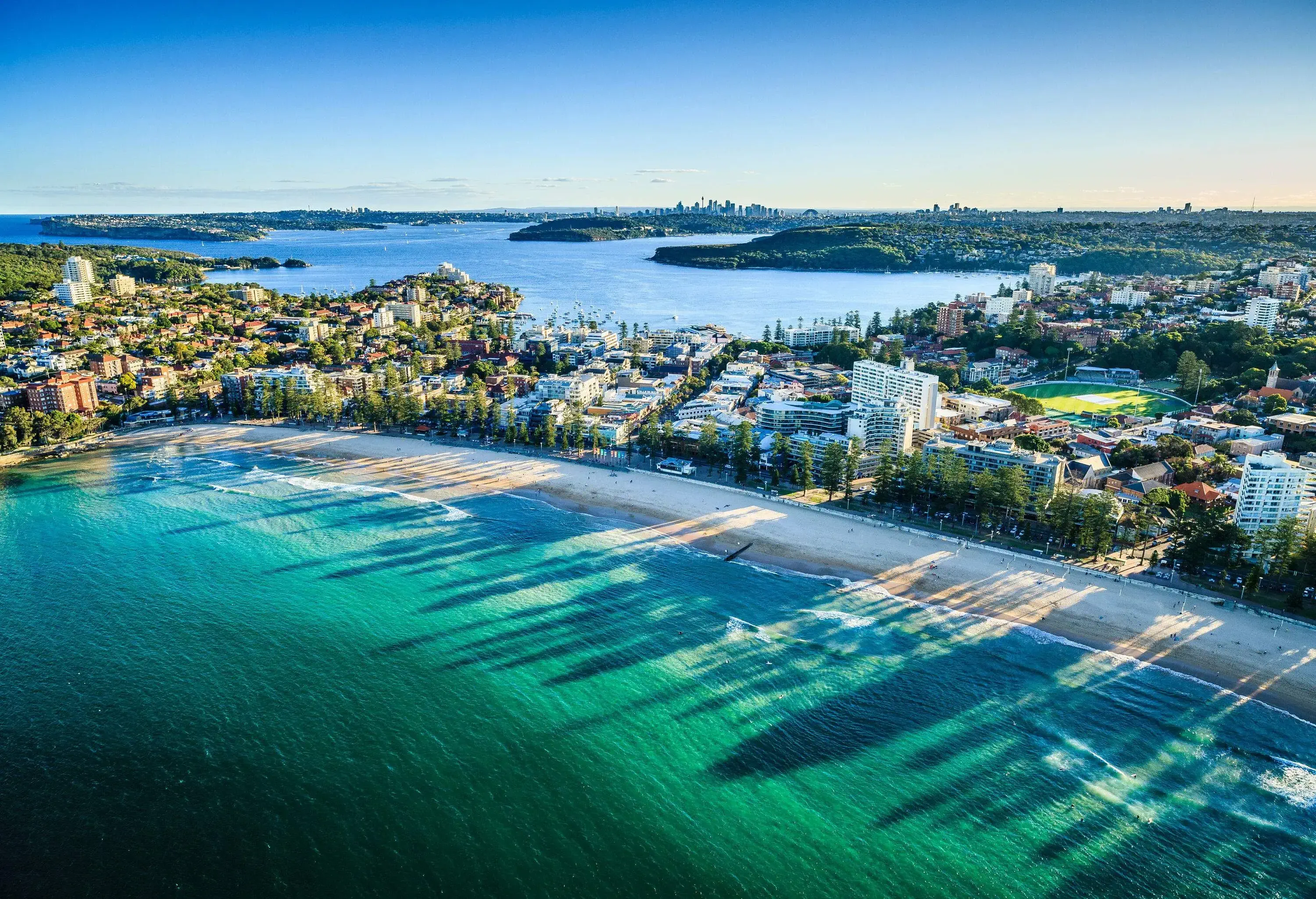 Aerial view of white sandy beach at dusk with shadow of buildings