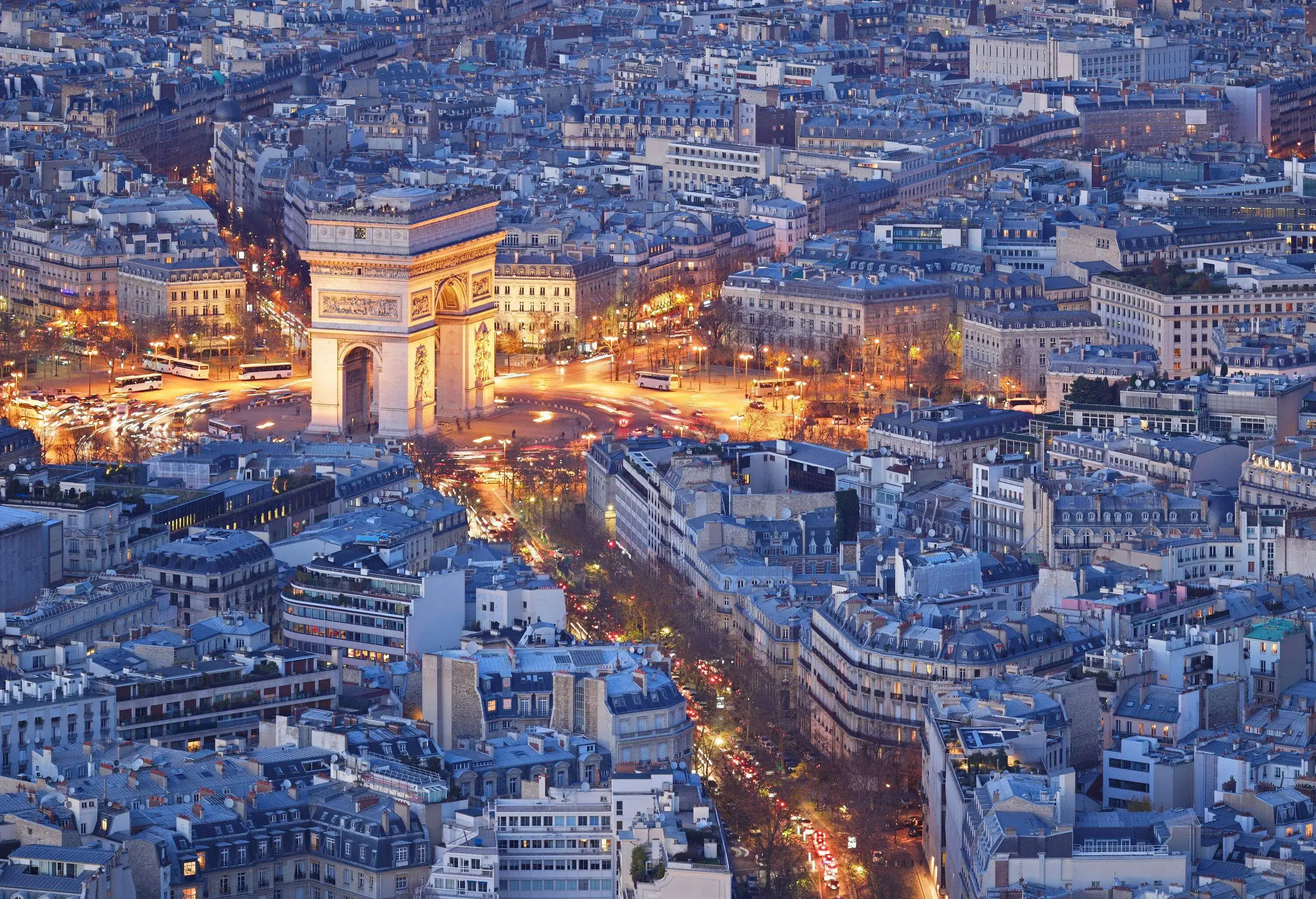 The Paris cityscape at night with the Arc de Triomphe surrounded by lit avenues.