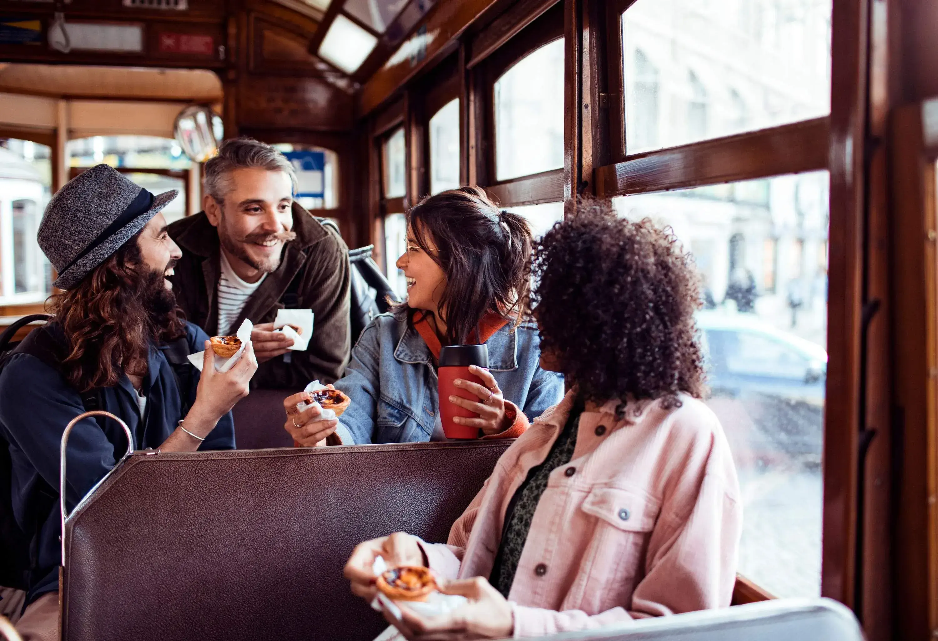 A cheerful group of friends shared laughter inside a tram, exchanging smiles while holding delicious tarts.
