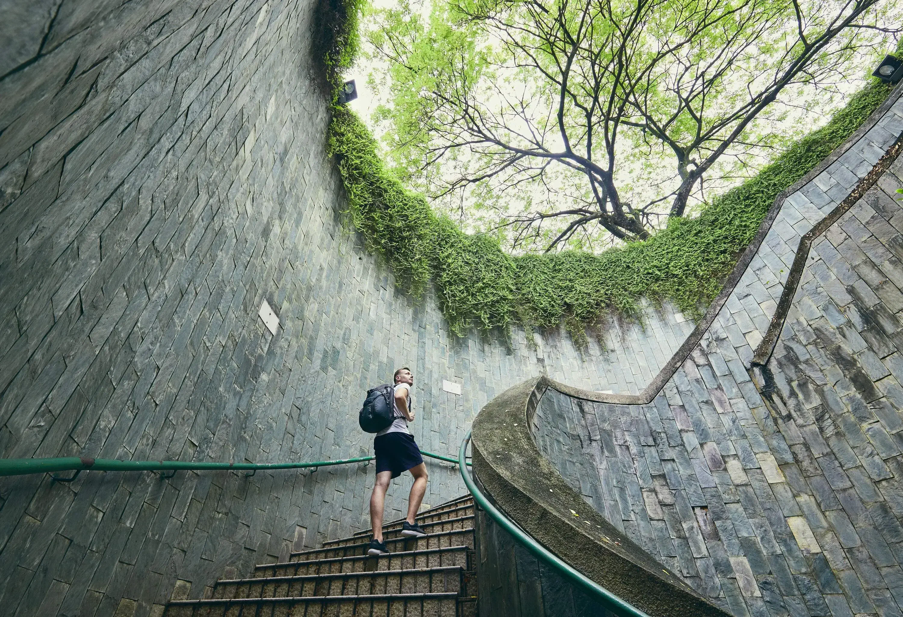 A male traveller with a backpack climbs the spiral staircase.