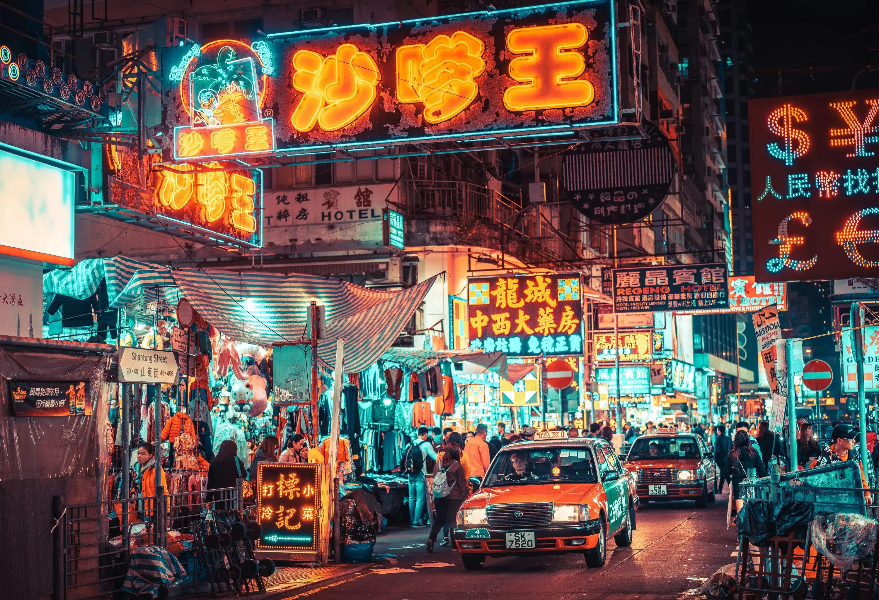 Signages illuminated in neon colours lit the bustling street lined with boutique shops at night. 