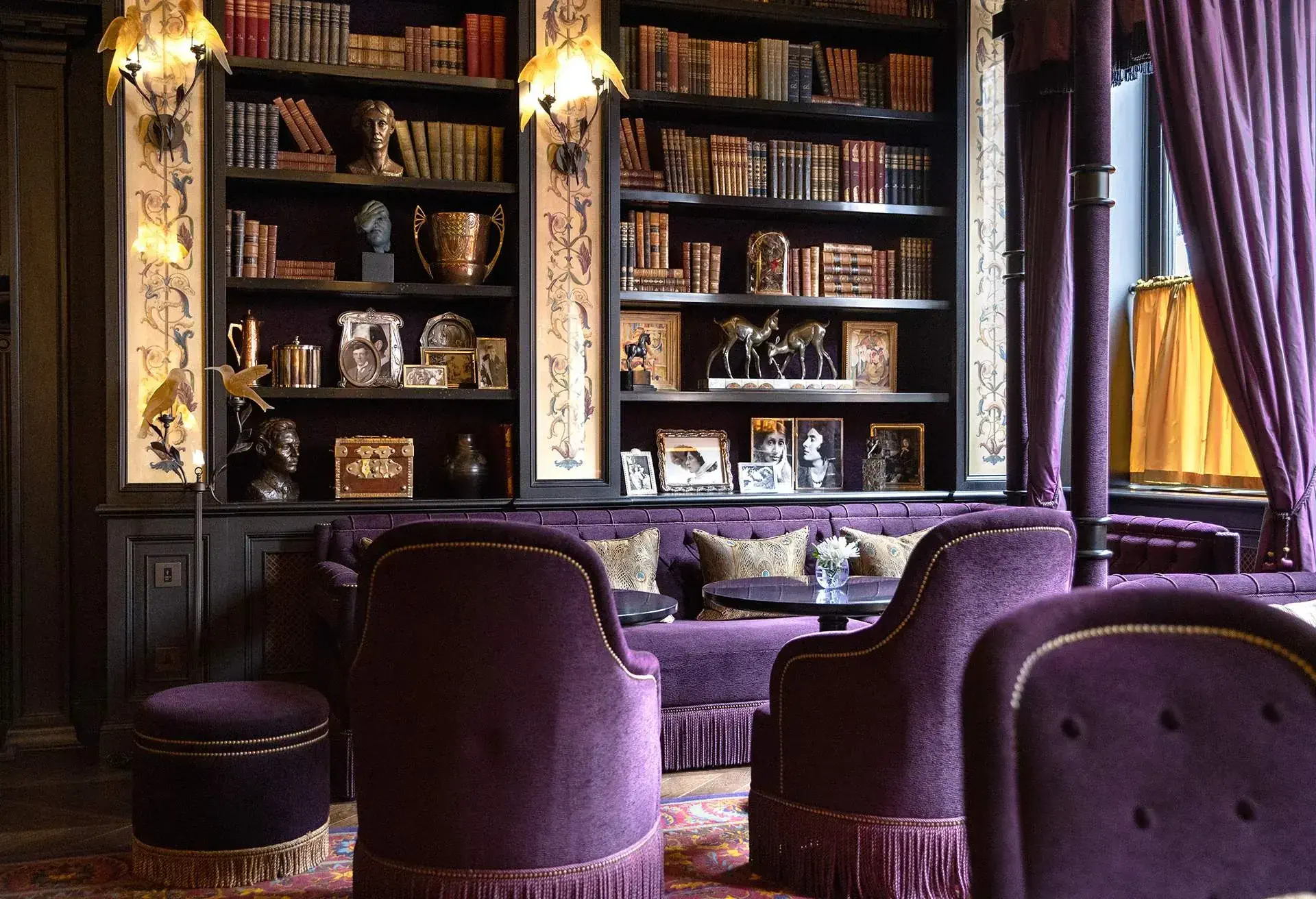 Interior sitting rooom decked in luxurious purple velvet with library in the background