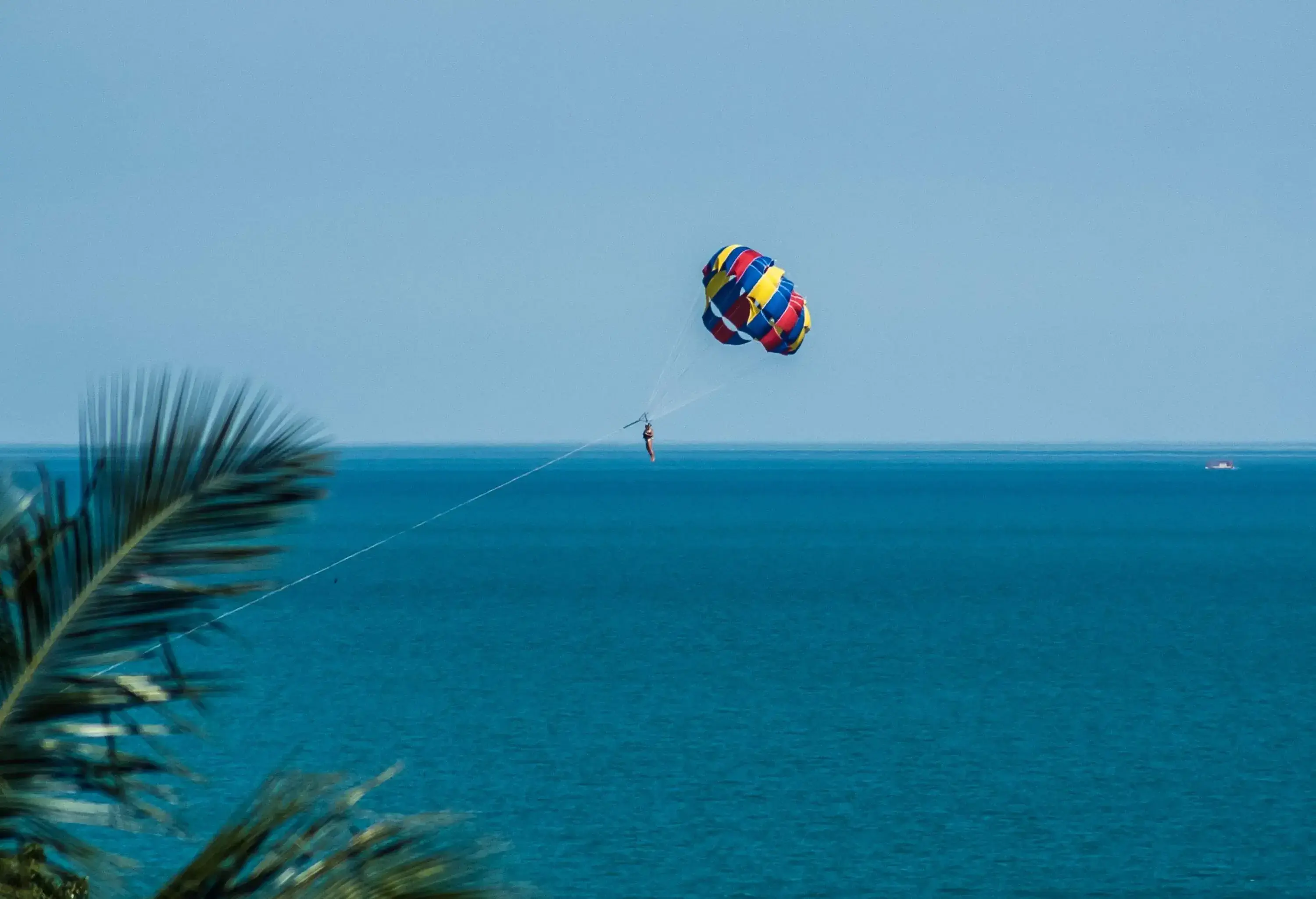 An individual in a colourful parasail over the tranquil blue sea.