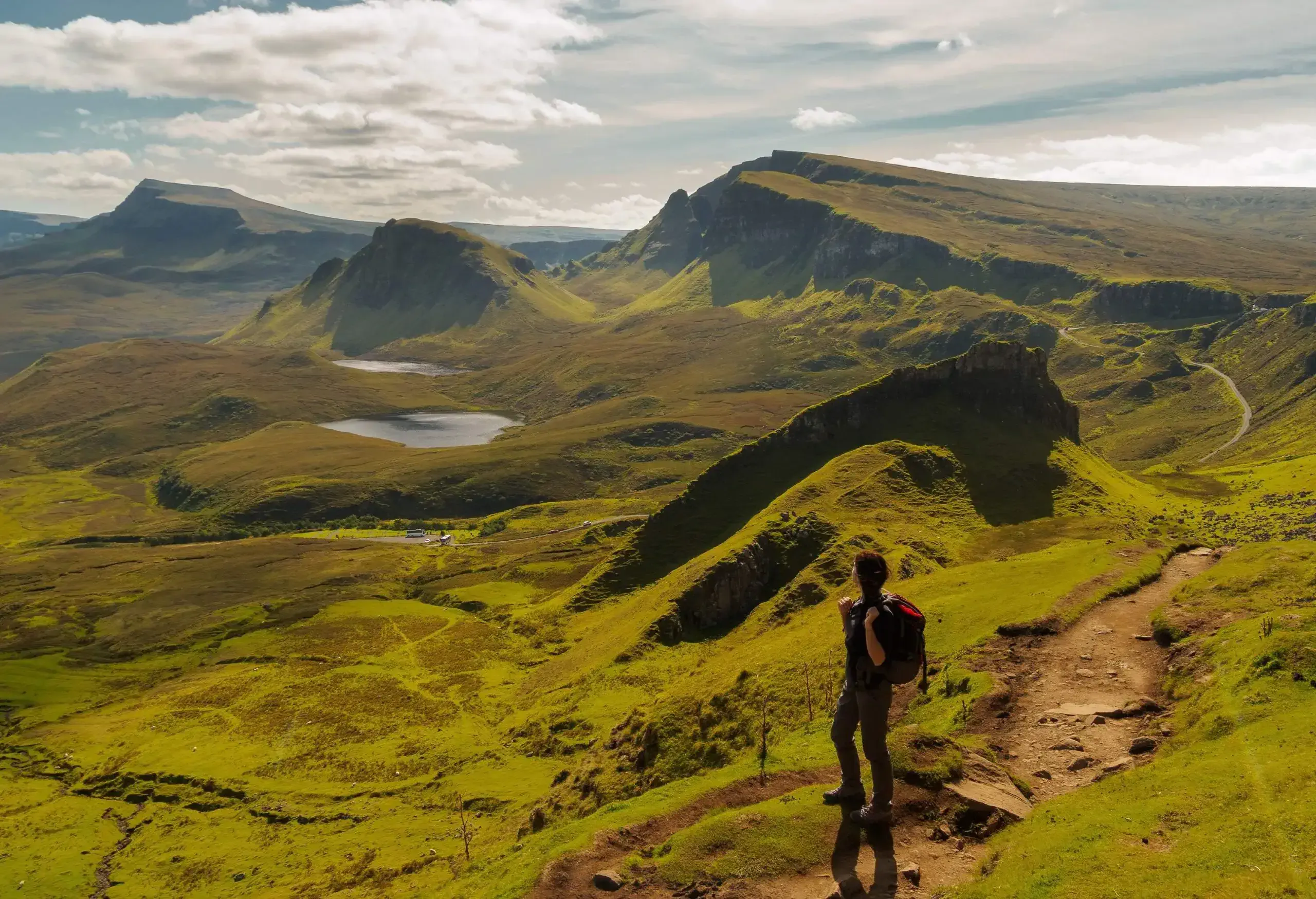 A female hiker standing and looking at the expansive landscape along the trail. 