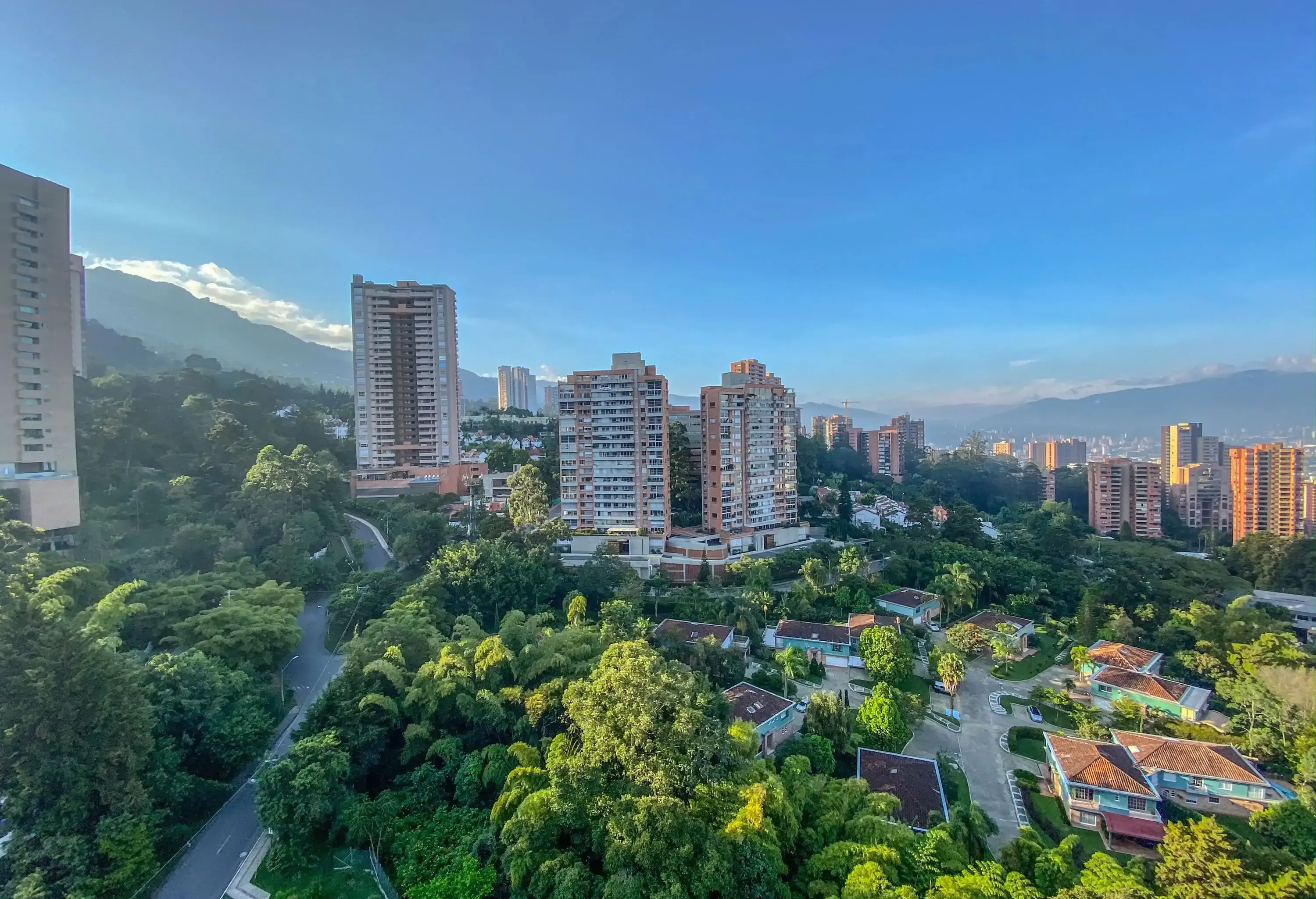 Panoramic view of city with high rise buildings surrounded by mountains and greenery