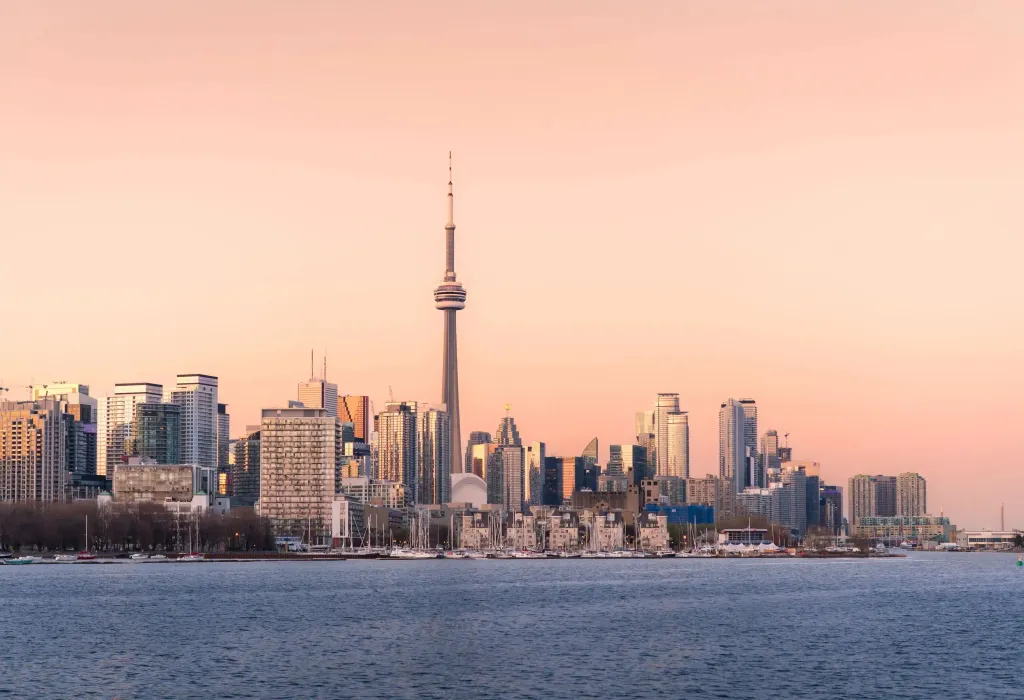 The Toronto skyline by the lake against a pink sky.