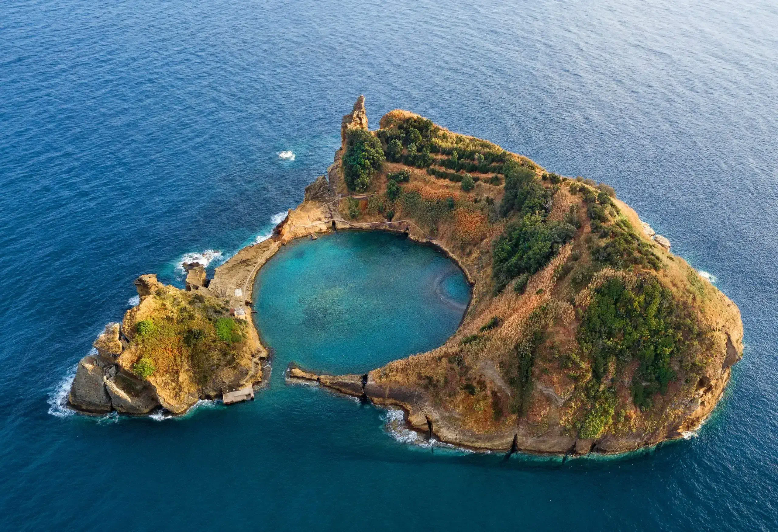 An islet with a sheltered bay surrounded by rugged slopes covered in vegetation.