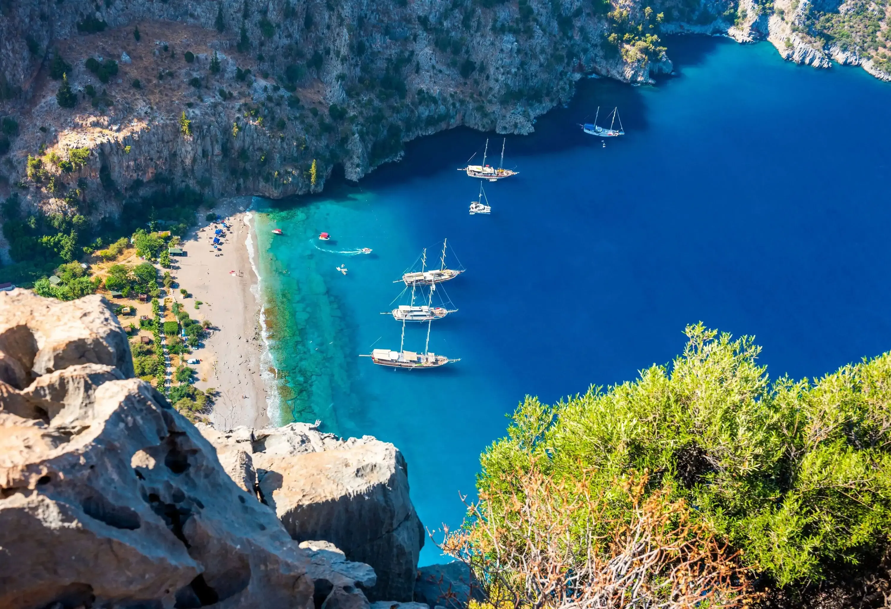 Boats on the serene blue beach in the valley of rocky mountains.