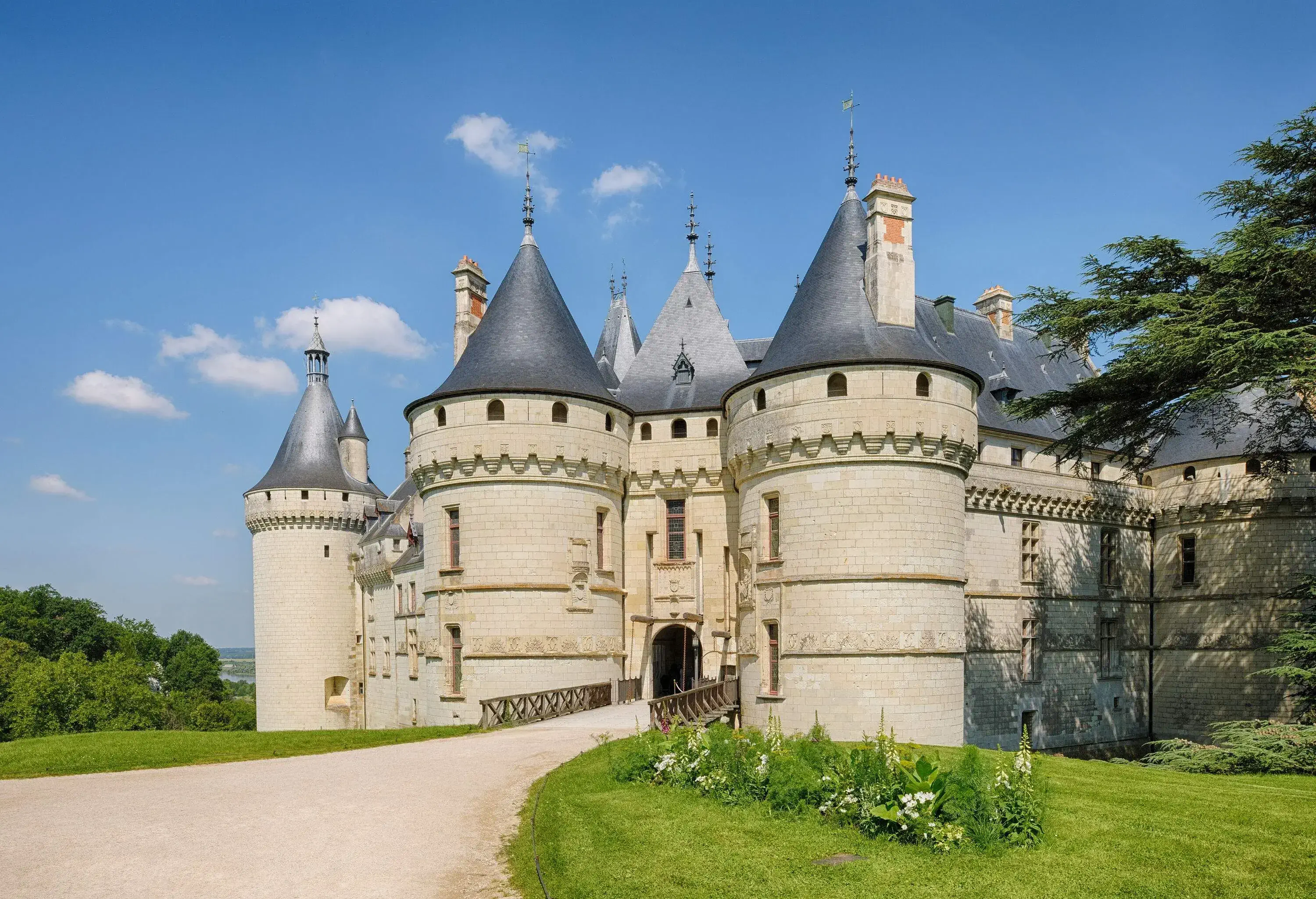 A masonry castle with cylindrical towers and cone-shaped roofs.
