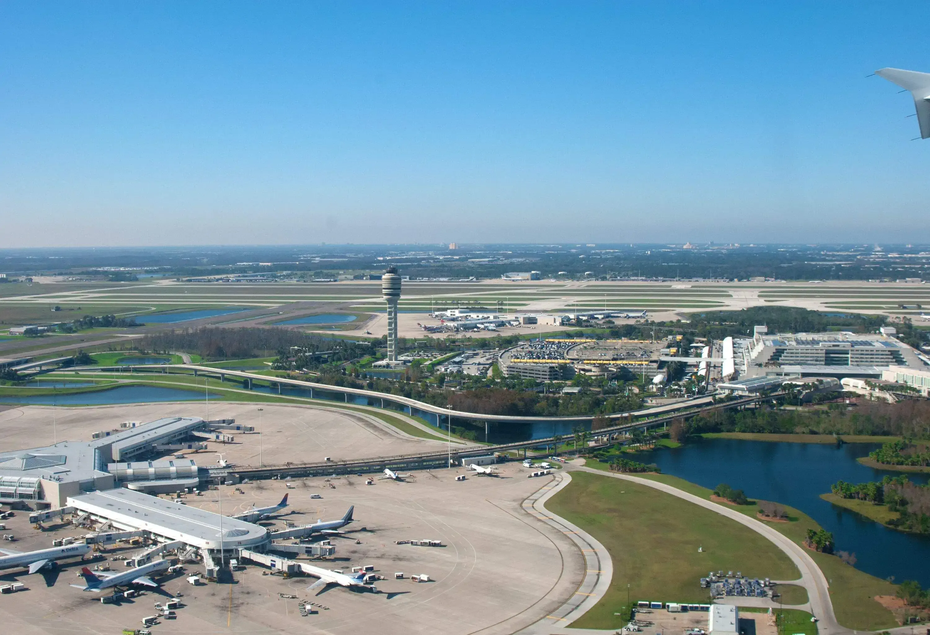 Aerial view of airport compound with control tower and small lake on the side on a sunny day