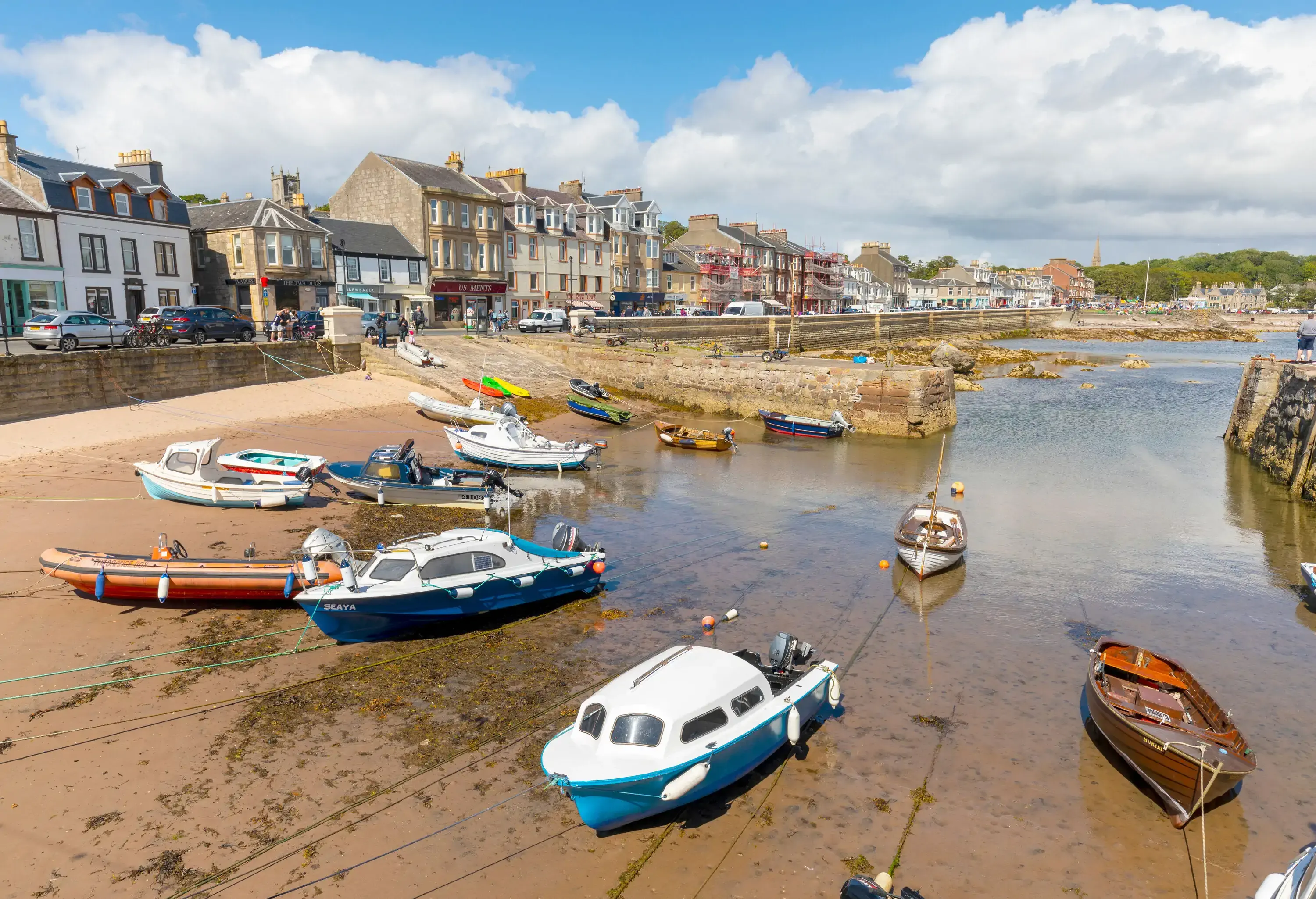 Boats moored at a beach on low tide by a traditional fishing village in Scotland