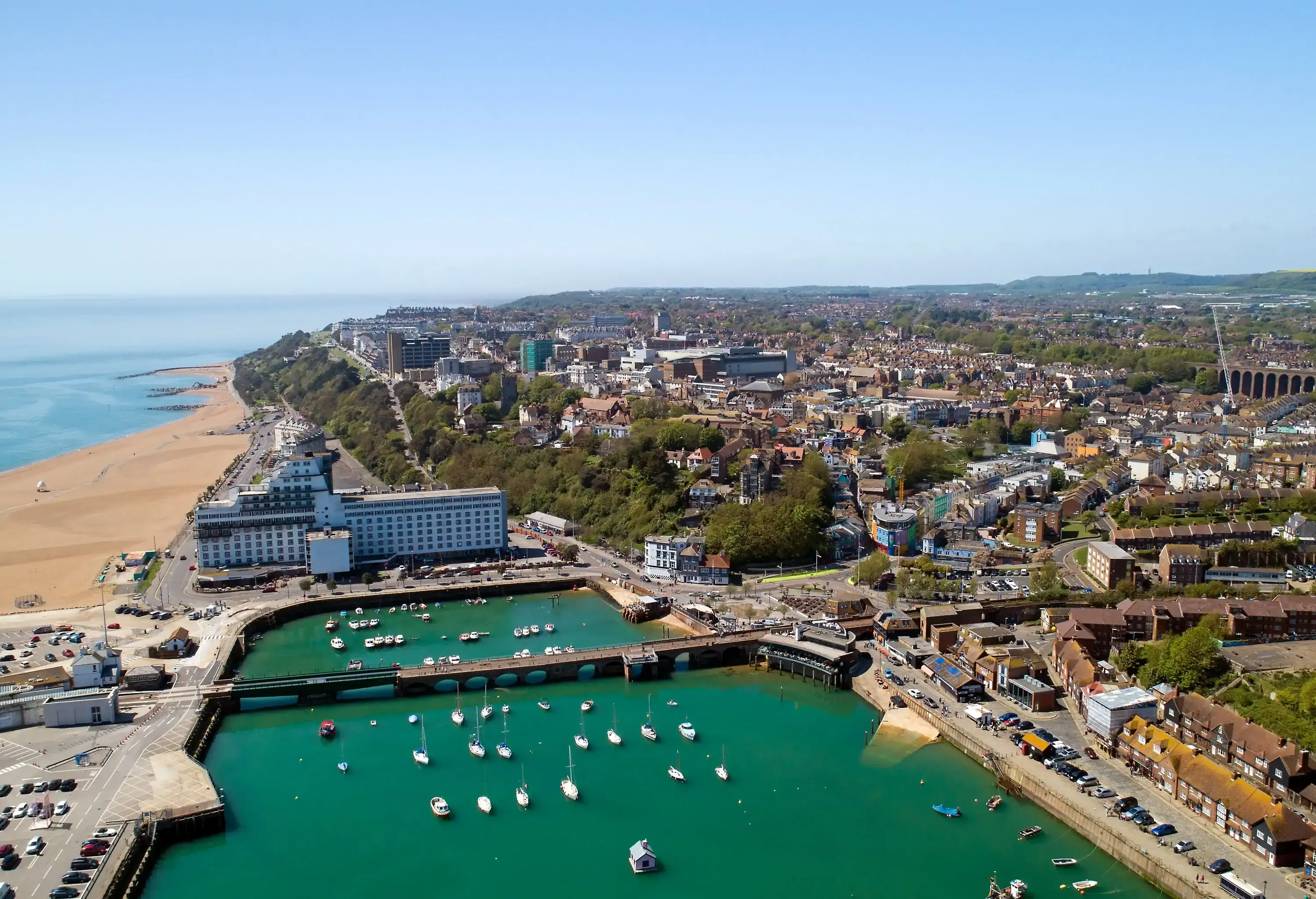 A seaside town with an arch bridge across a less crowded marina.