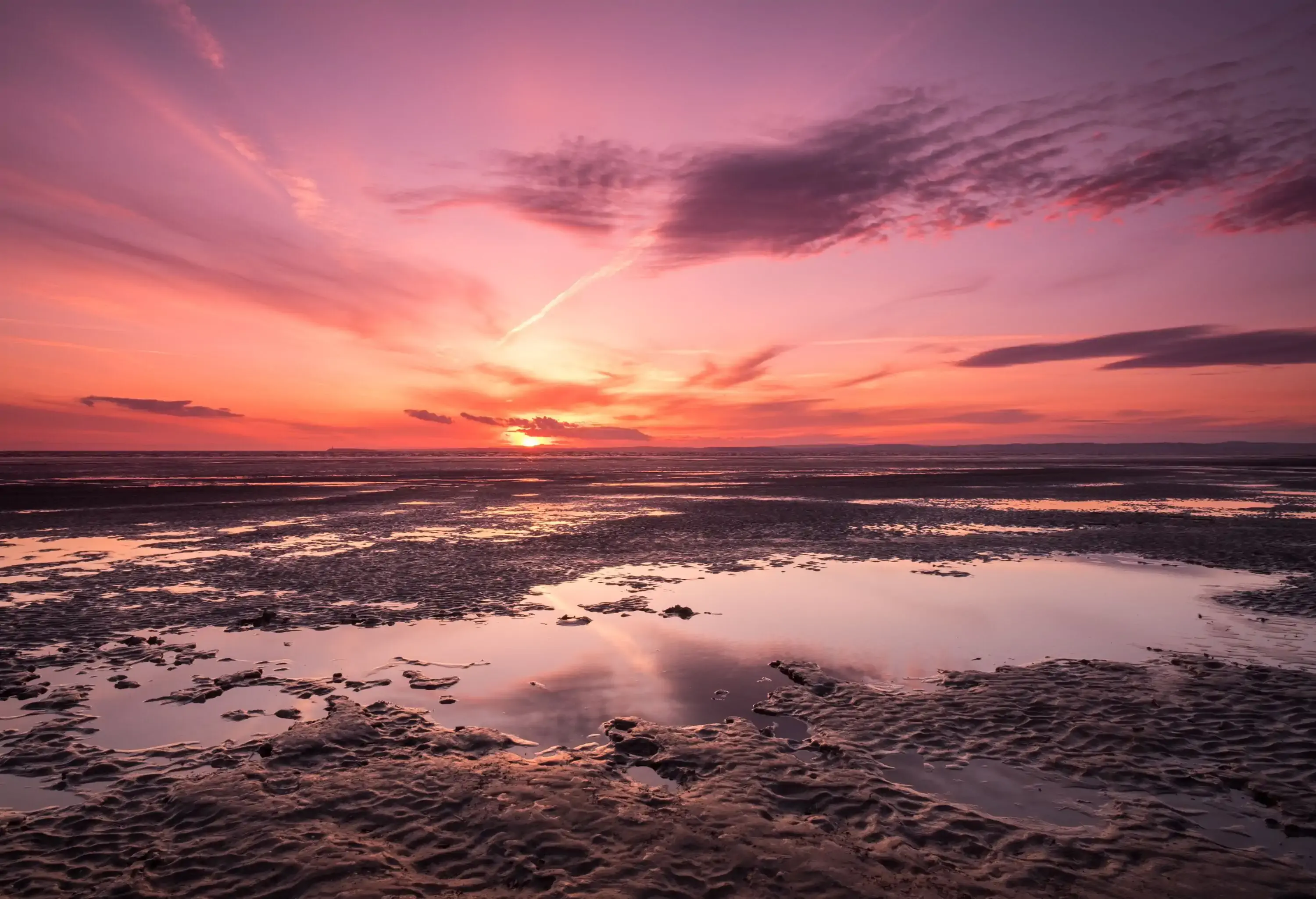 Sunset at sandy bay beach with the sky reflected on the mud flats