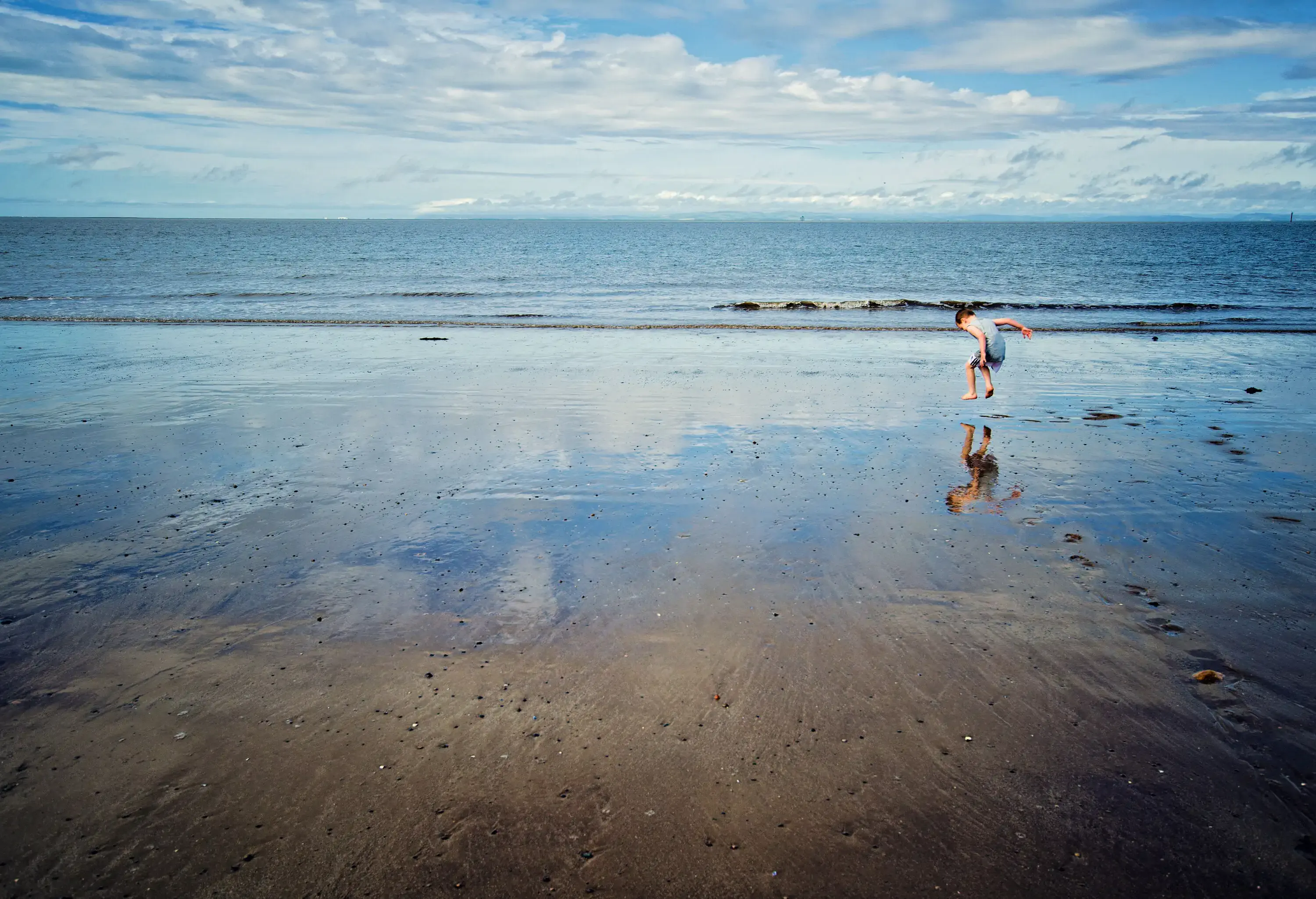 Young boy jumping on the beach at Fleetwood, Lancashire. UK
