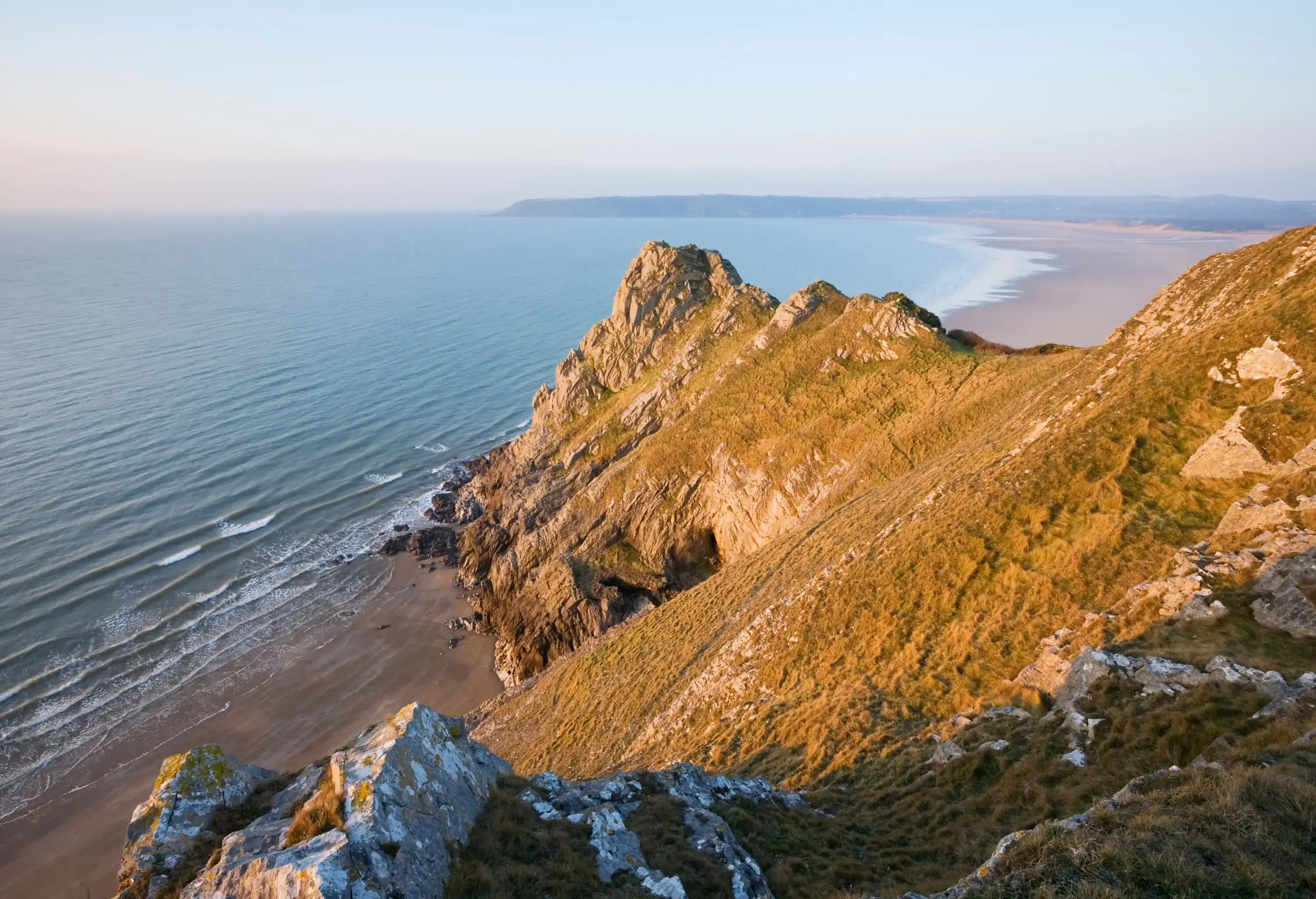 View of a sandy beach surrounded by rocks from the top of a hill