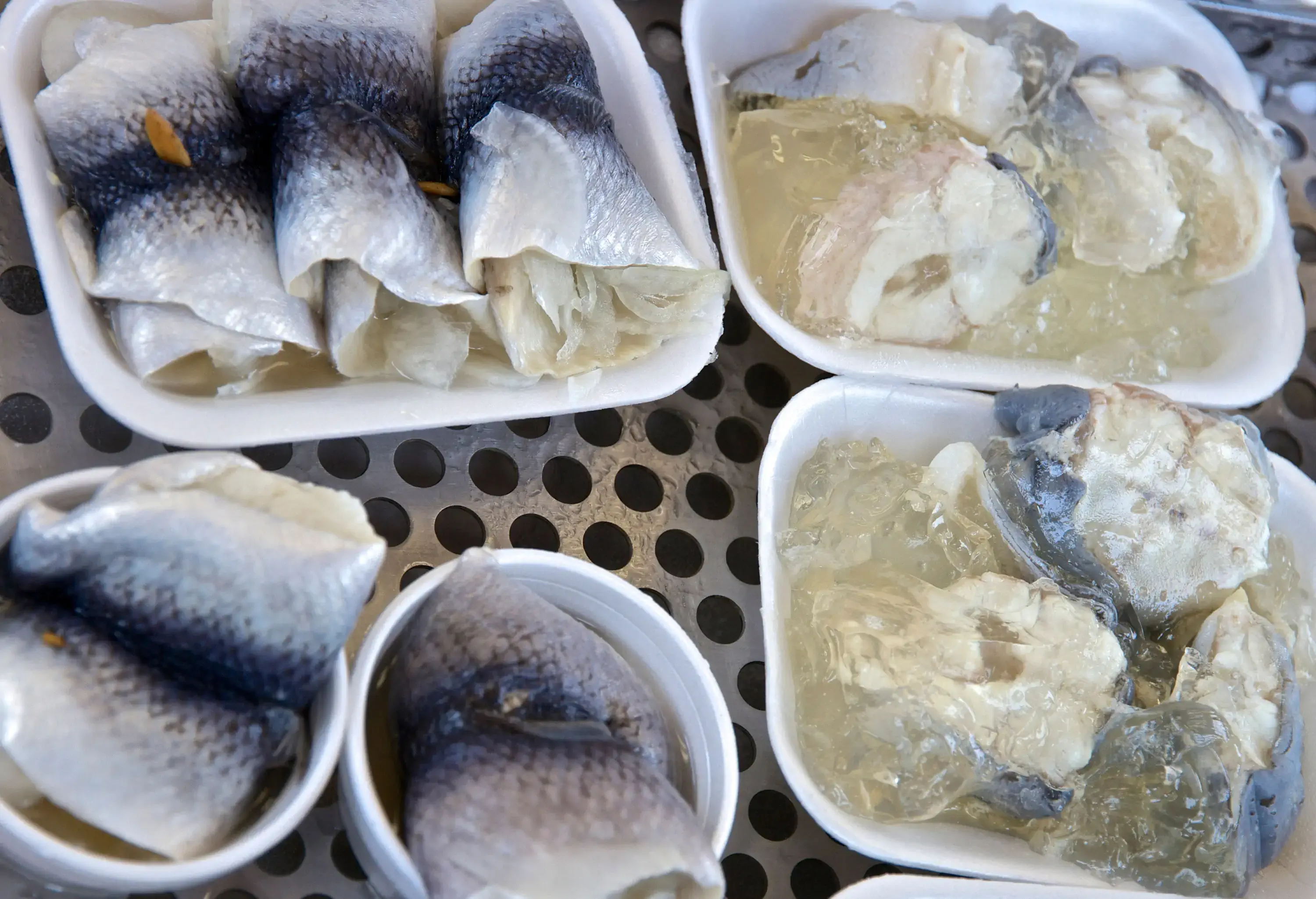 Fresh fish meat slices served on disposable cups and plates.