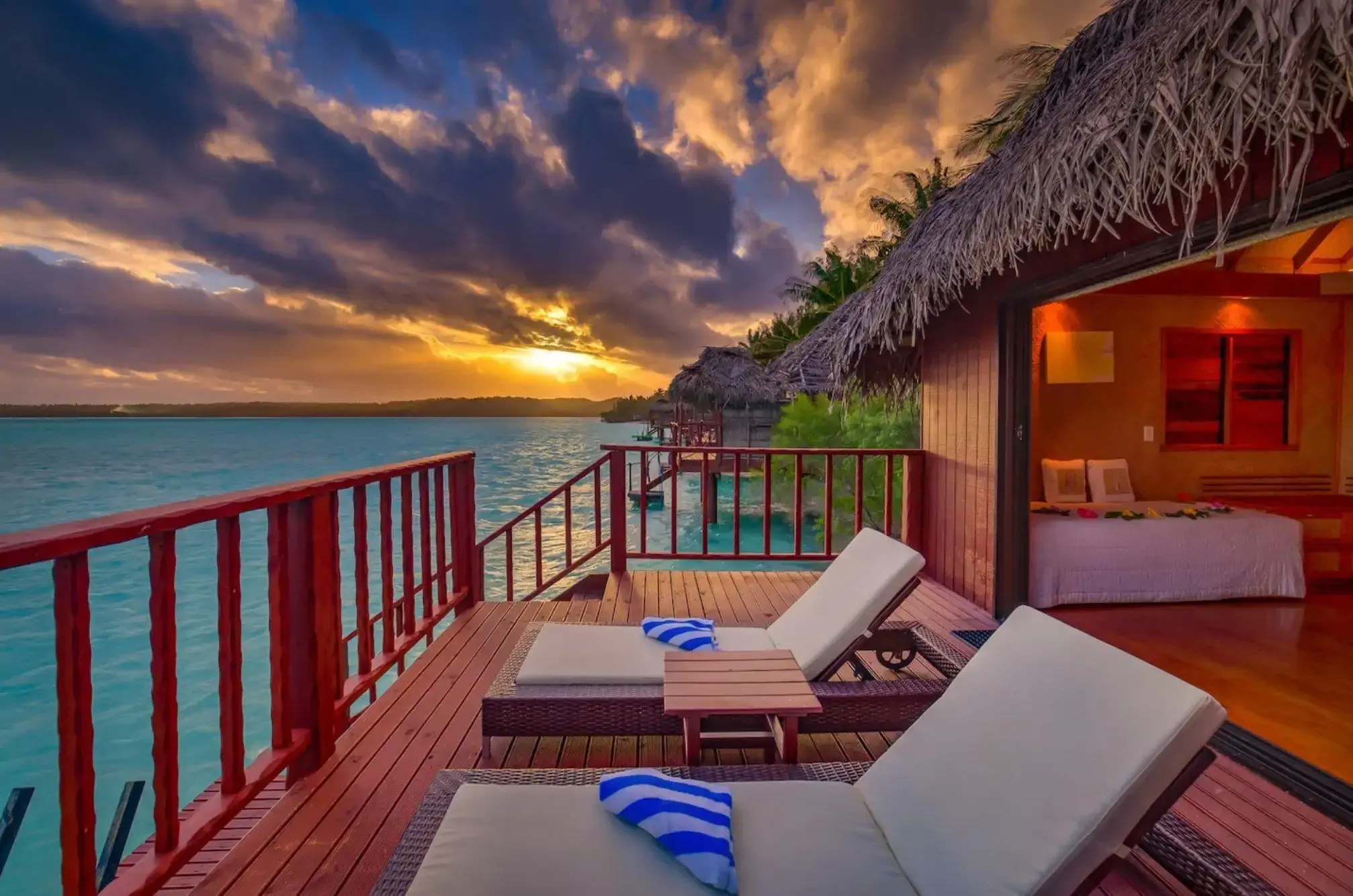 A cabin by the ocean with palapa roof and two sun loungers, at sunset