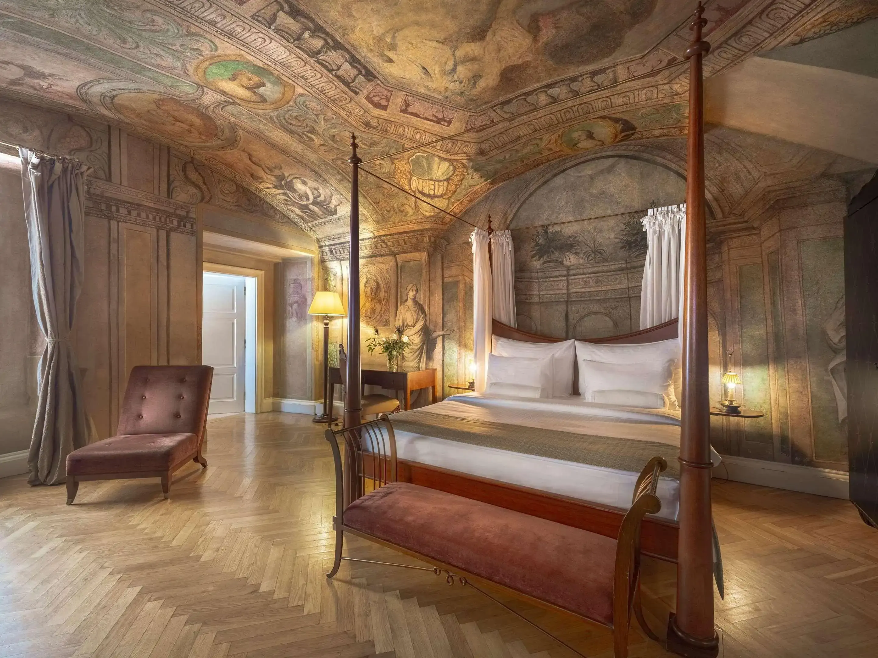 A classic room covered in frescoes with a wooden four-poster-bed