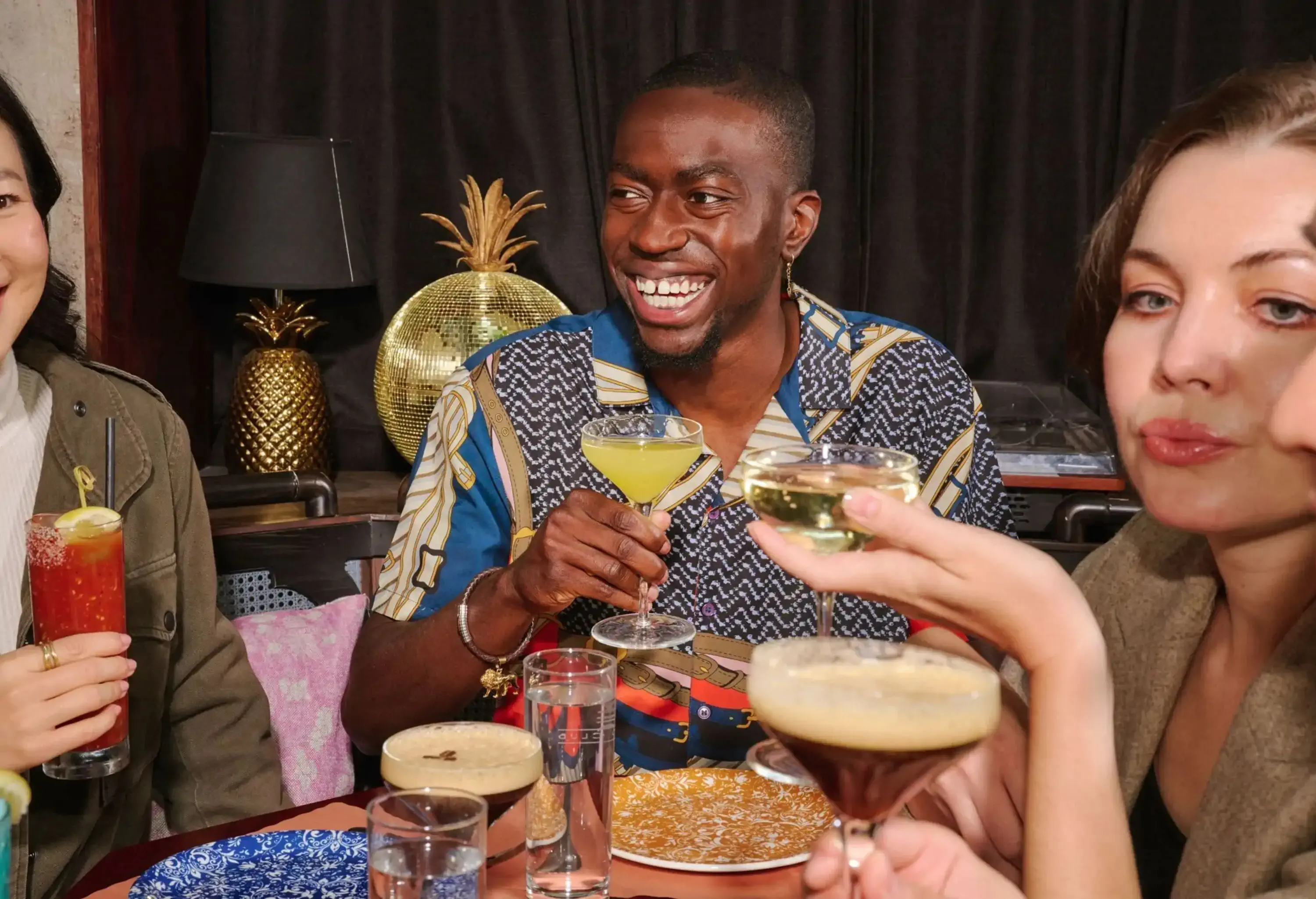 A circle of friends drinking cocktails in a restaurant.