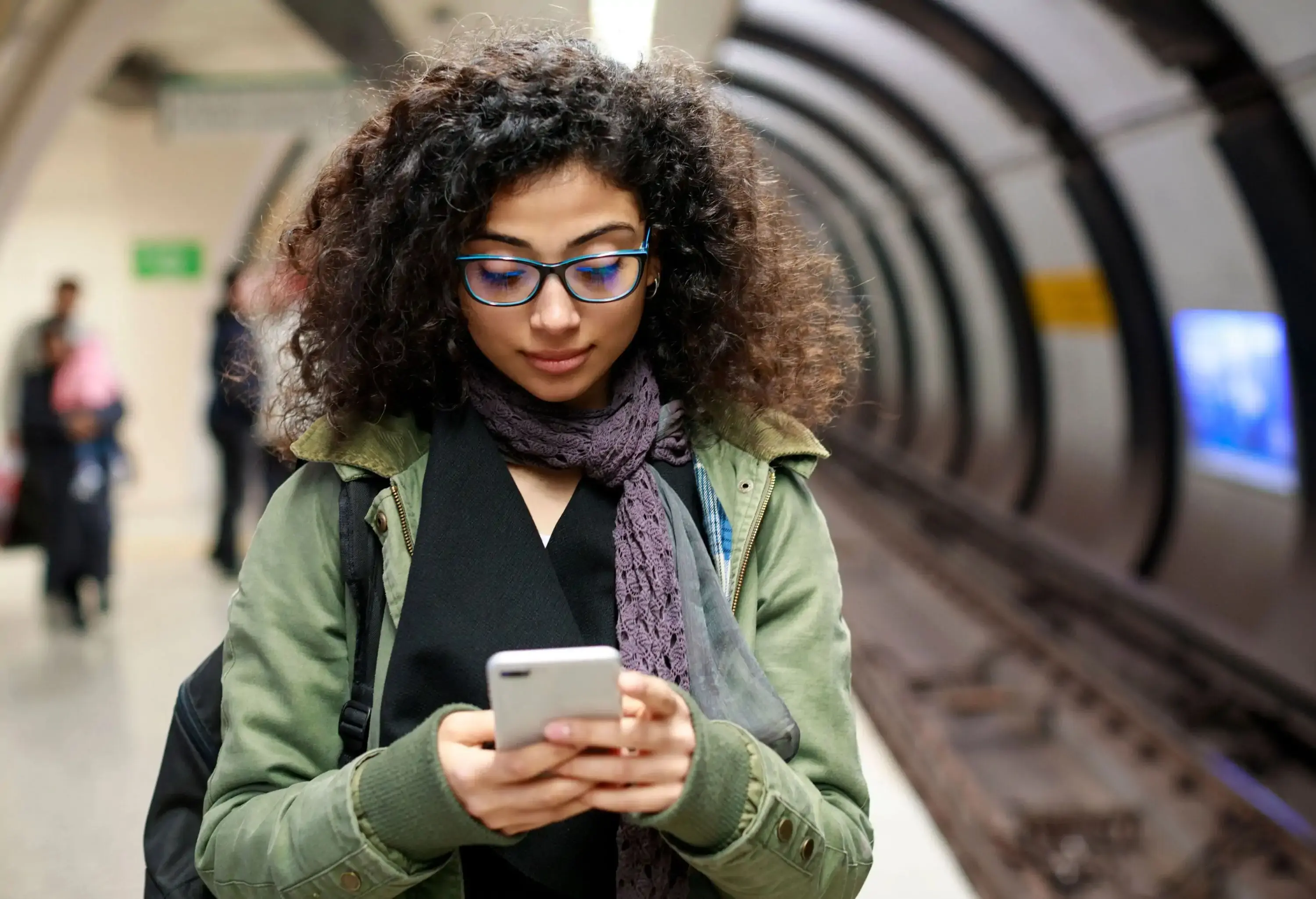 Young female commuter using mobile phone in the subway station