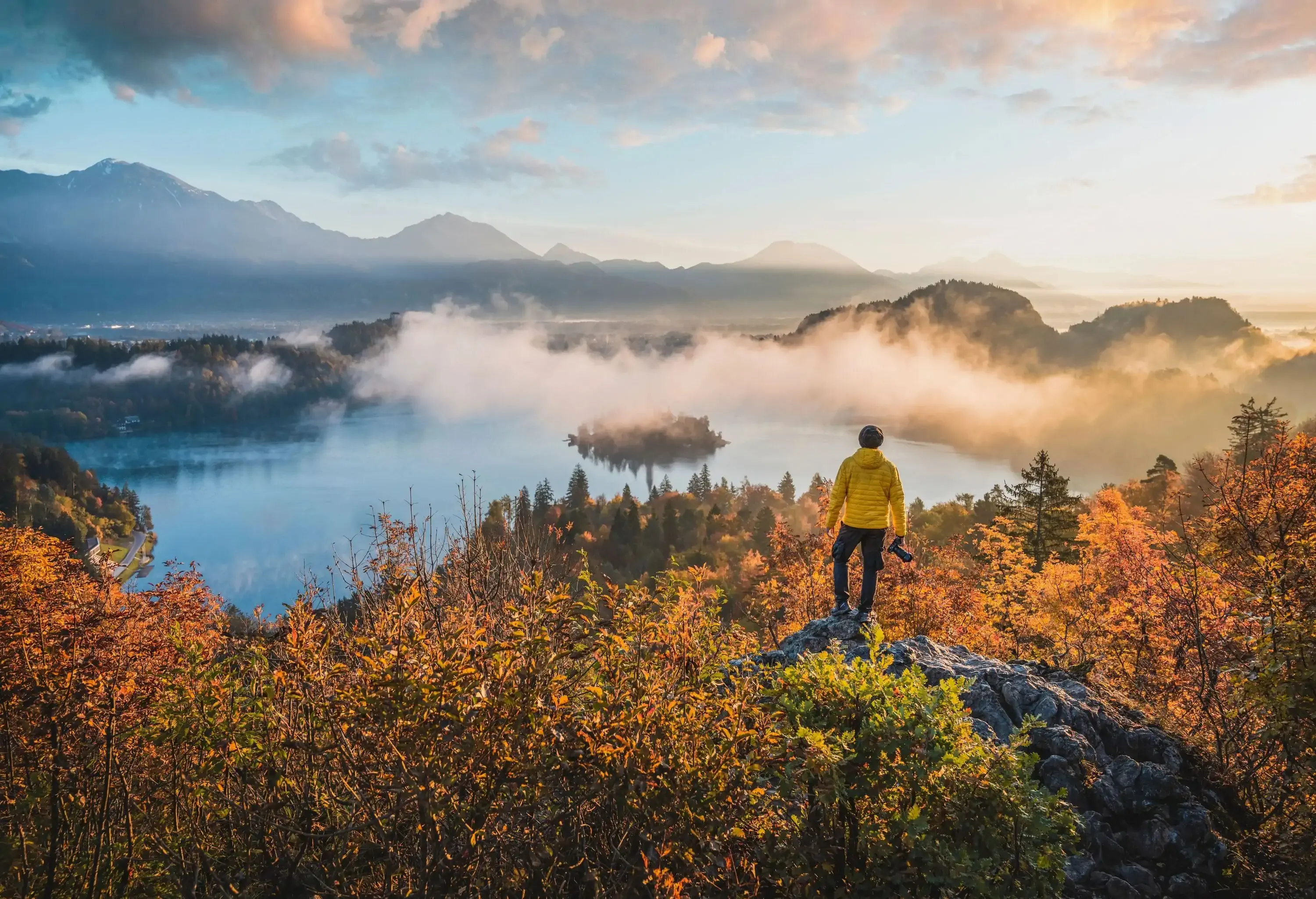 Man standing on top of a rock admiring the view of lake Bled, Slovenia