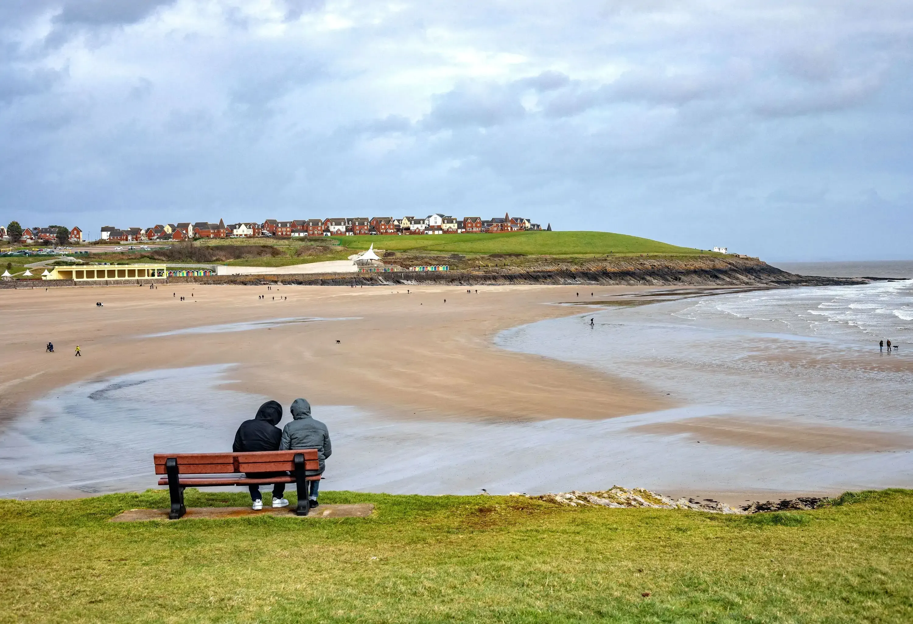 Couple Sitting on Bench and Looking at View on Whitmore Bay in Wales.