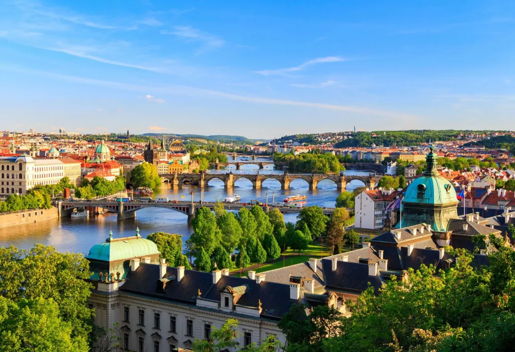 The meandering Vltava River gracefully winds through the town, adorned with picturesque bridges that span its tranquil waters and trees dotting its banks.