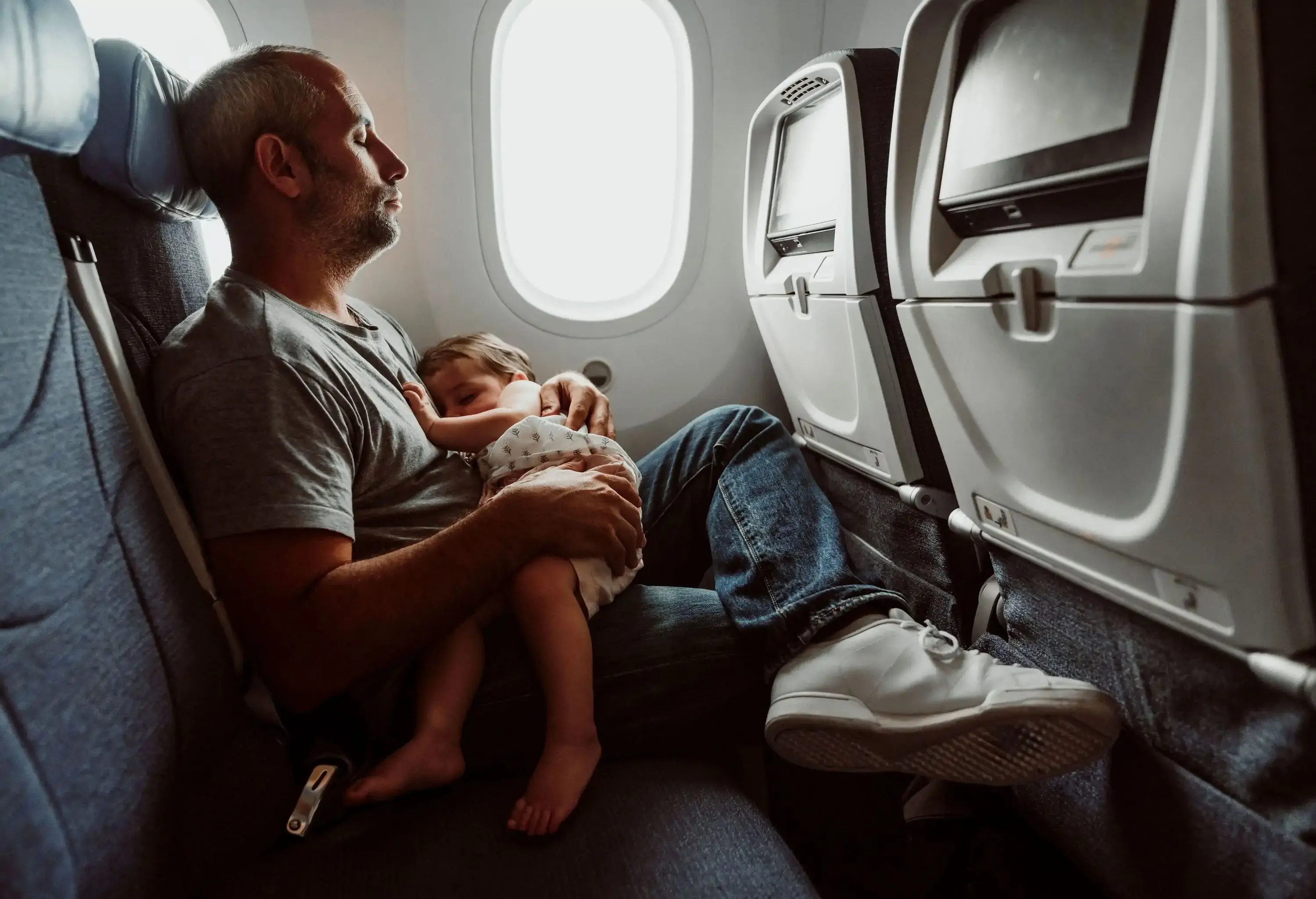 Father and baby sleeping on a plane