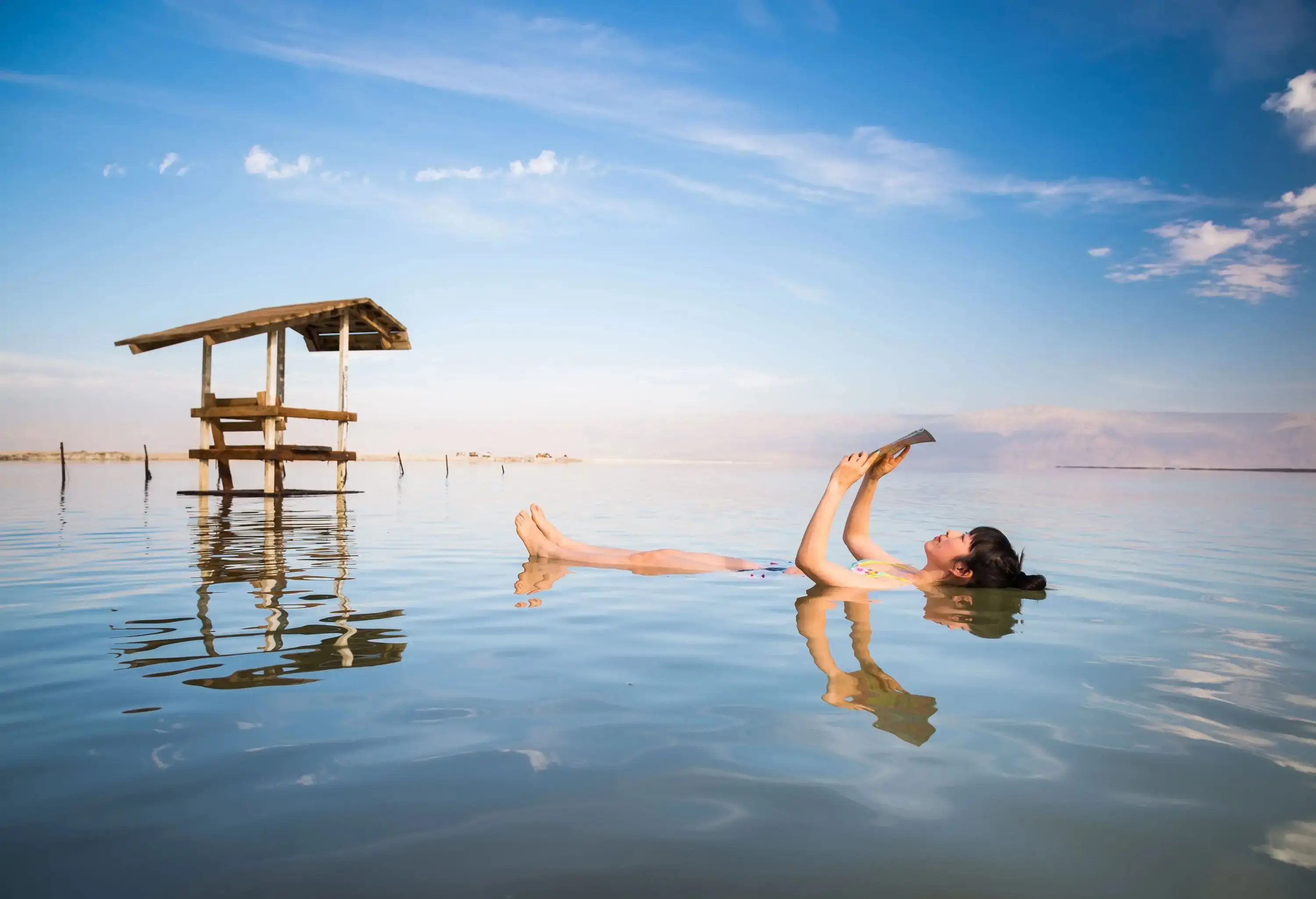 A woman reading a book while floating in water.