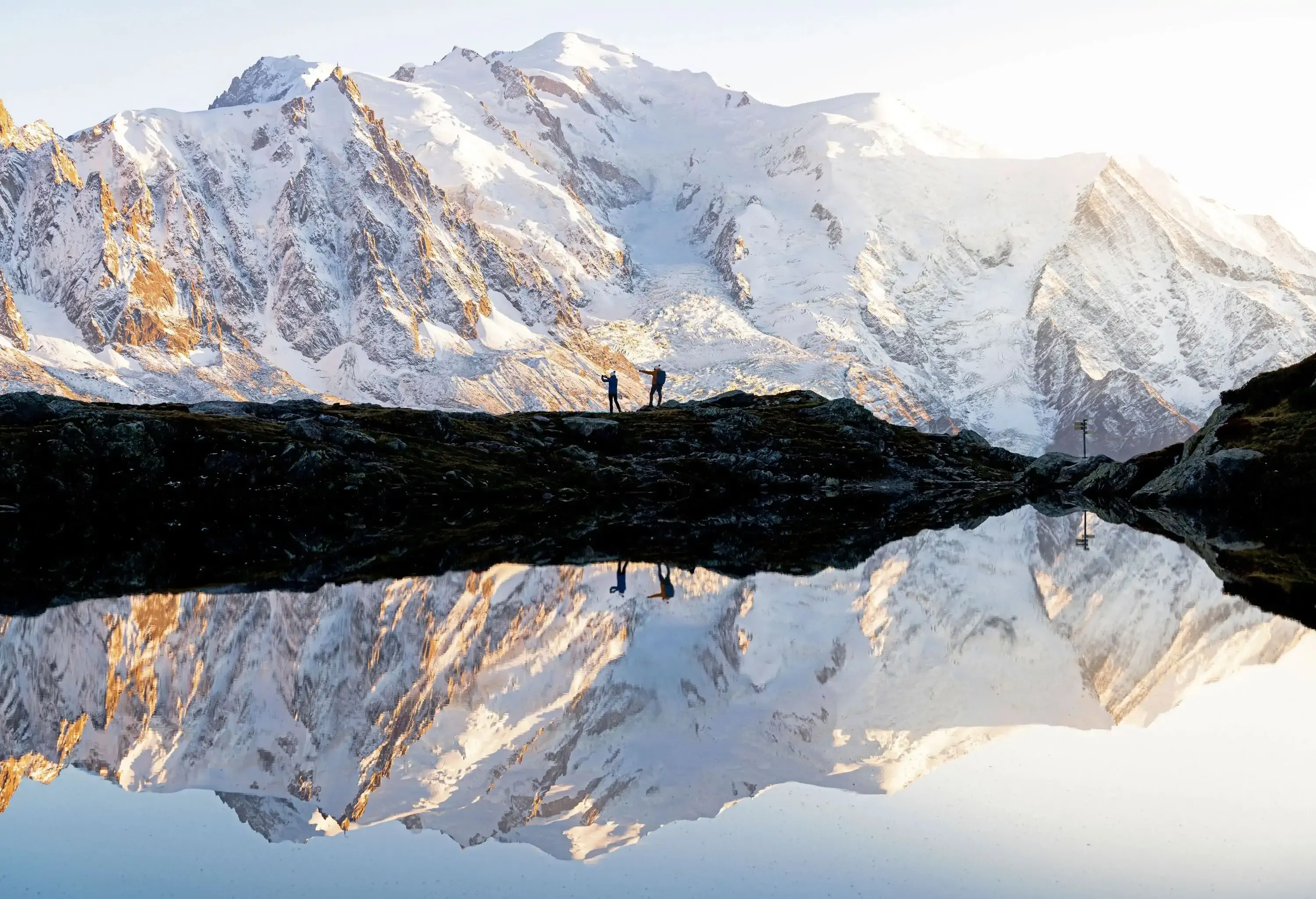 Silhouettes of people admiring  sunset over Mont Blanc covered with snow mirrored in Lacs des Cheserys, Haute Savoie, France