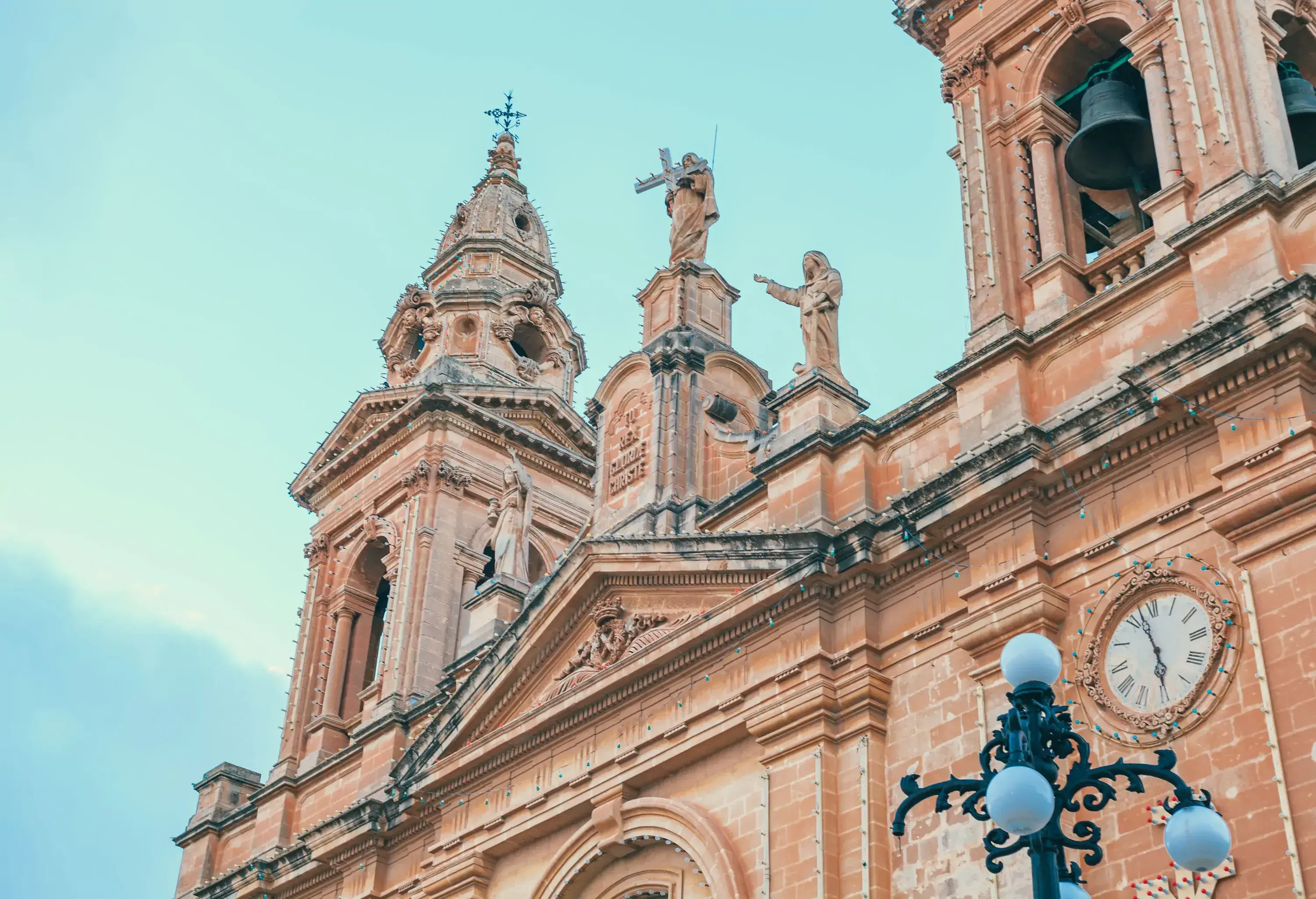 A church with intricately carved bell towers, rooftop religious statues, and steeples with crucifix finials.