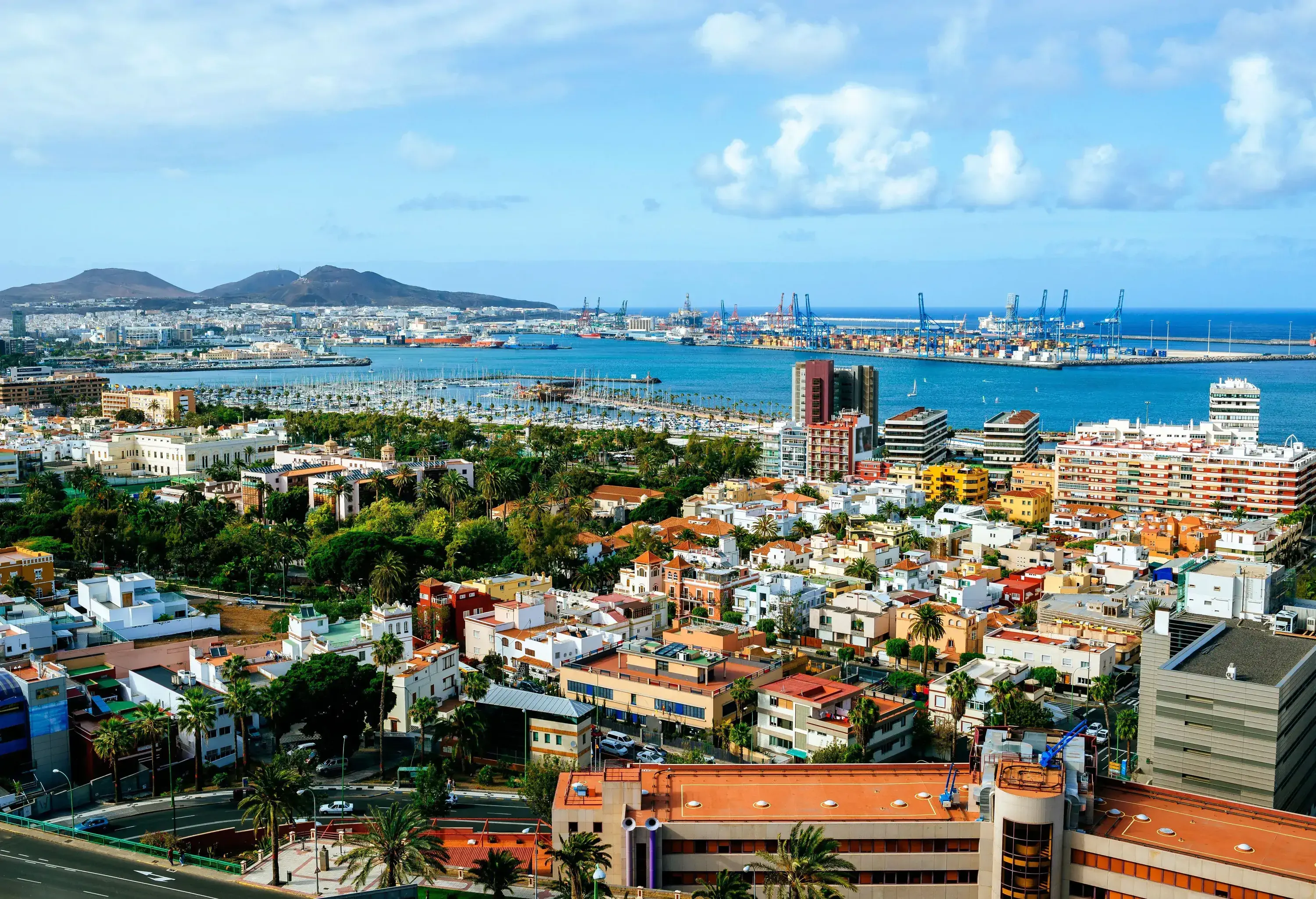 A stunning town, full of life, with a pier and mountains in the distance, situated on the coast.