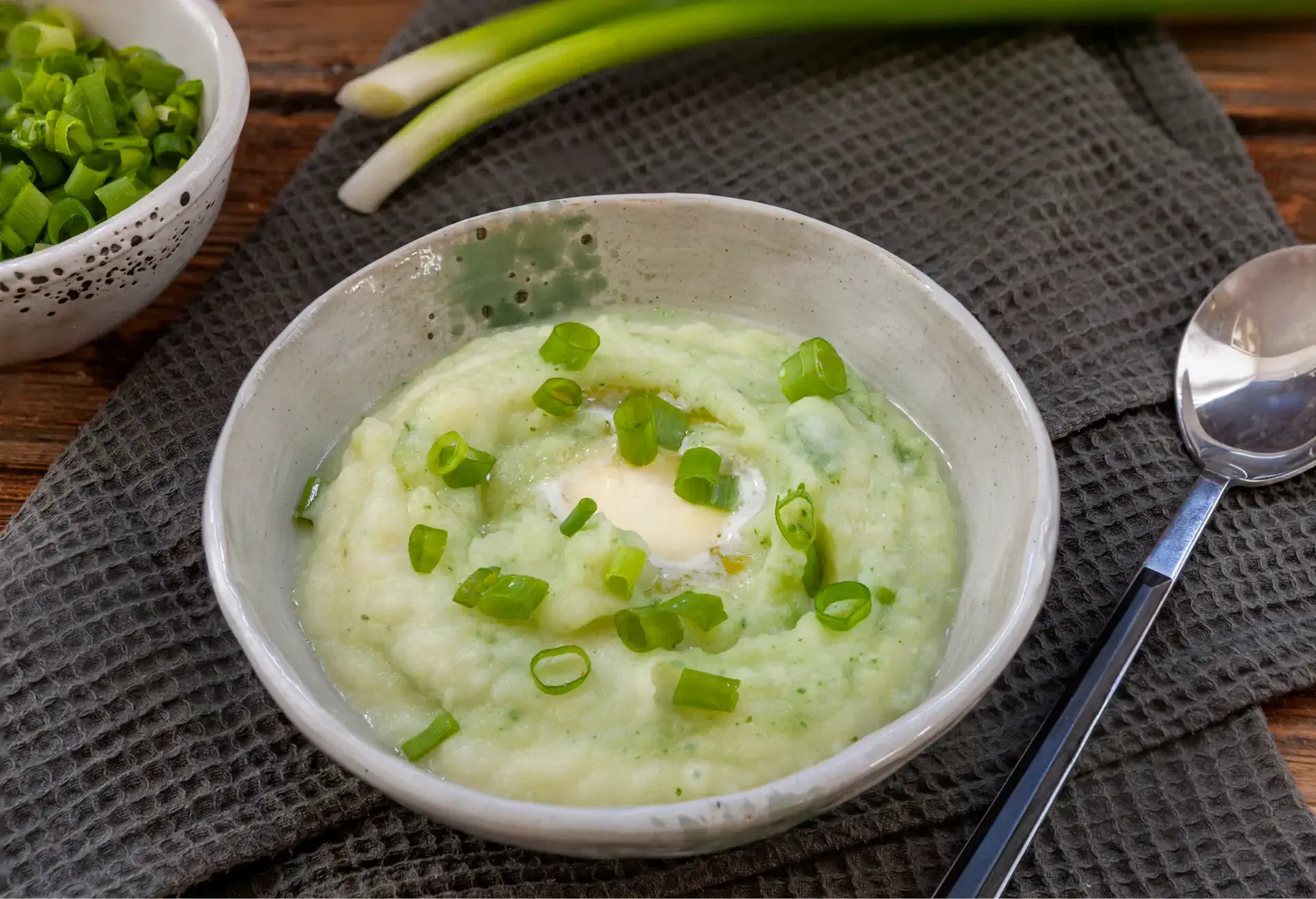 Bowl of colcannon mashed potatoes topped with butter and chopped green onions.
