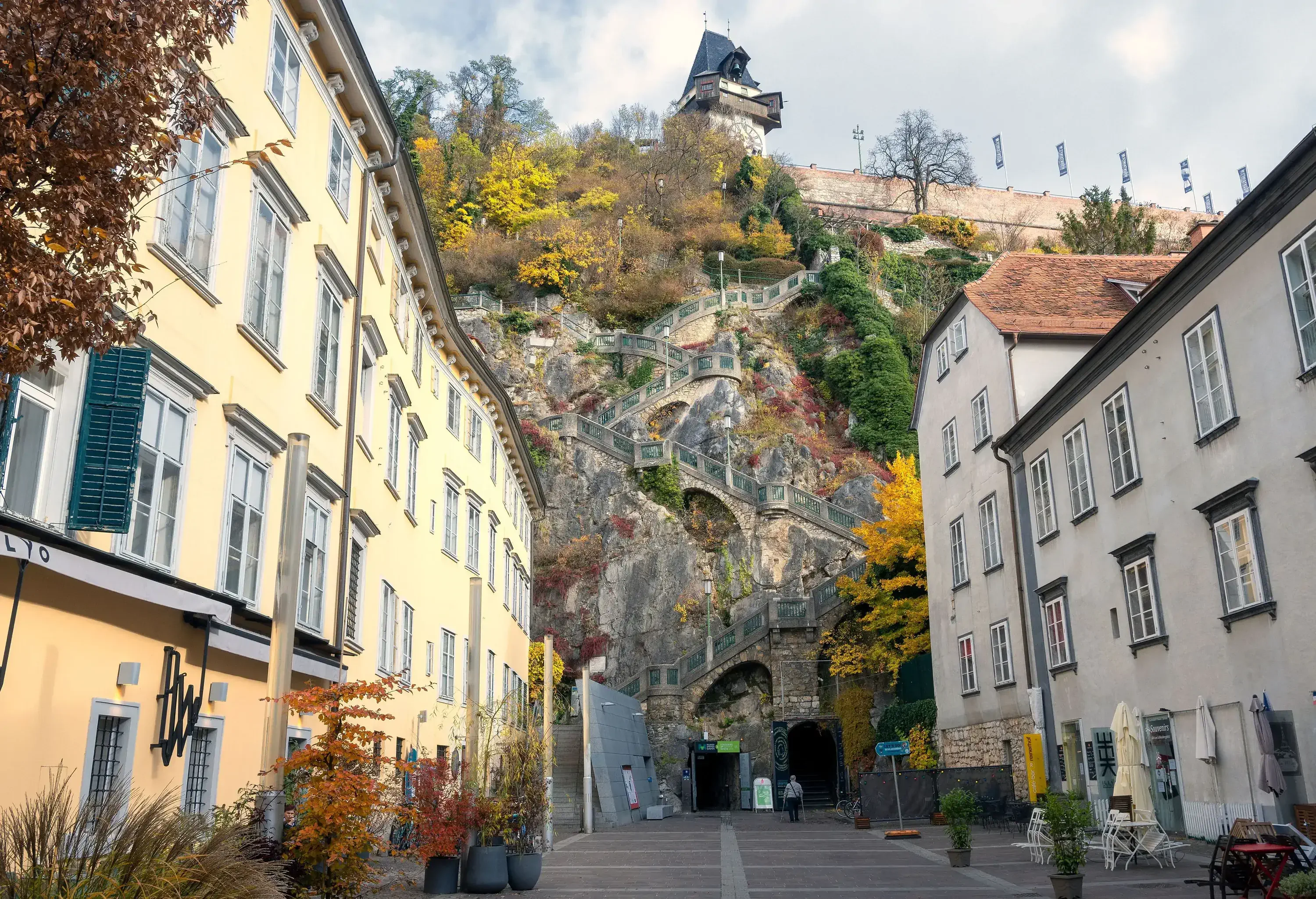 A medieval clock tower and garden on top of a hill, accessible by a stairway that winds its way down the hills.